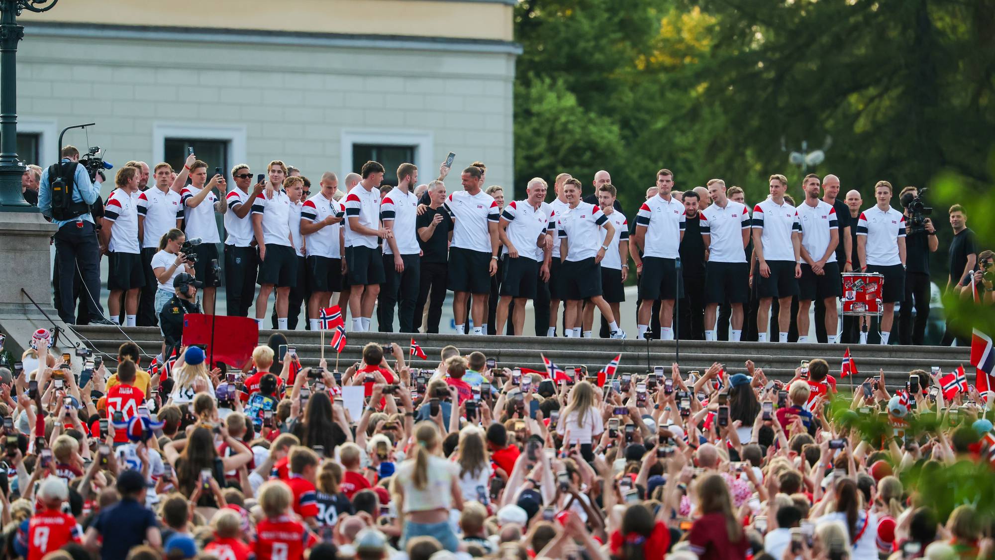 Det norske herrelandslaget i fotball hilser en folkemengde fra Slottsbalkongen. (Bildebeskrivelsen er laget av en KI-tjeneste)