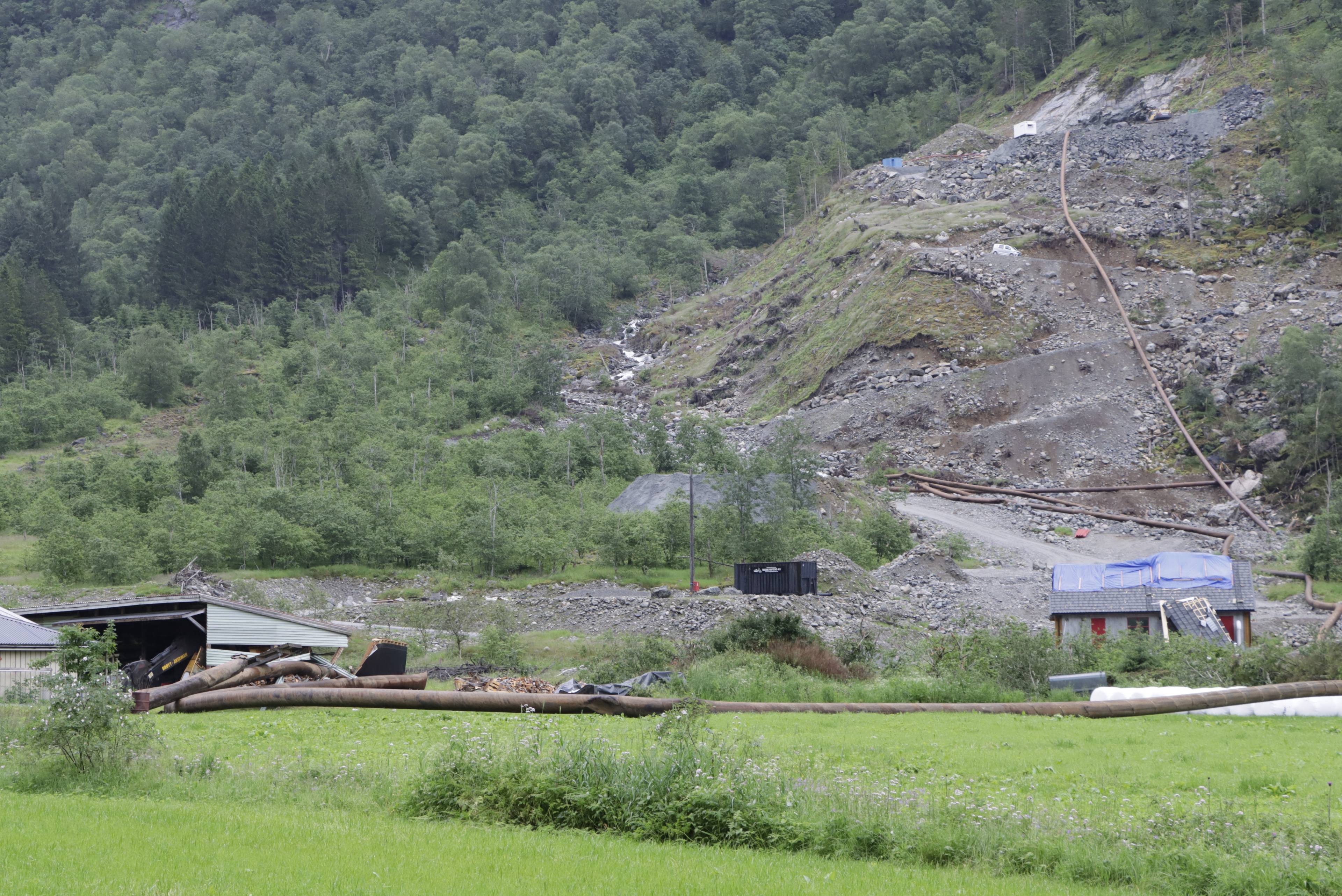 Skredområde med store rørledninger og skadede bygg i en fjellside. (Bildebeskrivelsen er laget av en KI-tjeneste)