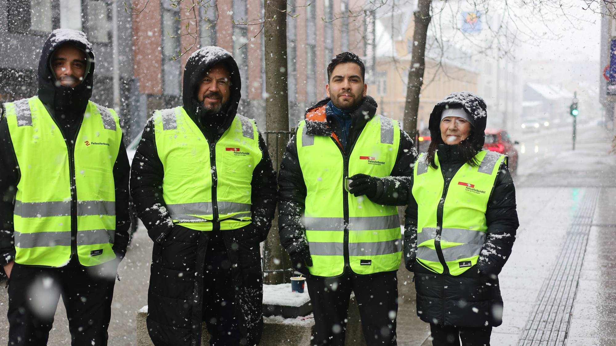 Fire streikende medlemmer av Fellesforbundet står i snøvær