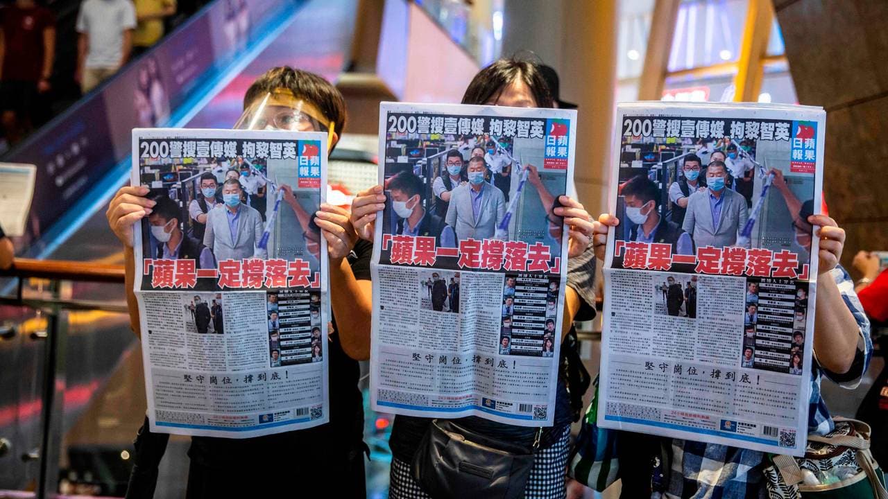 Demonstranter holder opp en kopi av avisen Apple Daily etter at politiet i Hongkong hadde ransaket avisens kontorer.