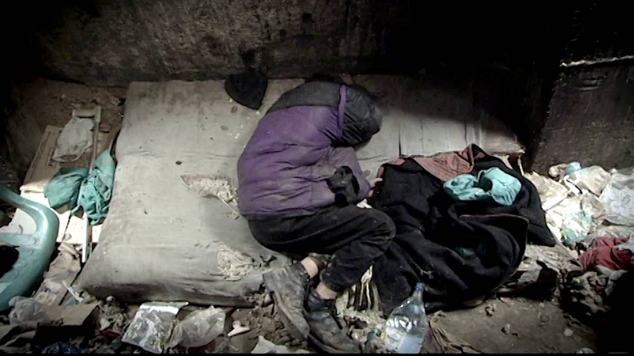 En gutt ligger og sover nede i kloakken i Bucuresti på 90-tallet