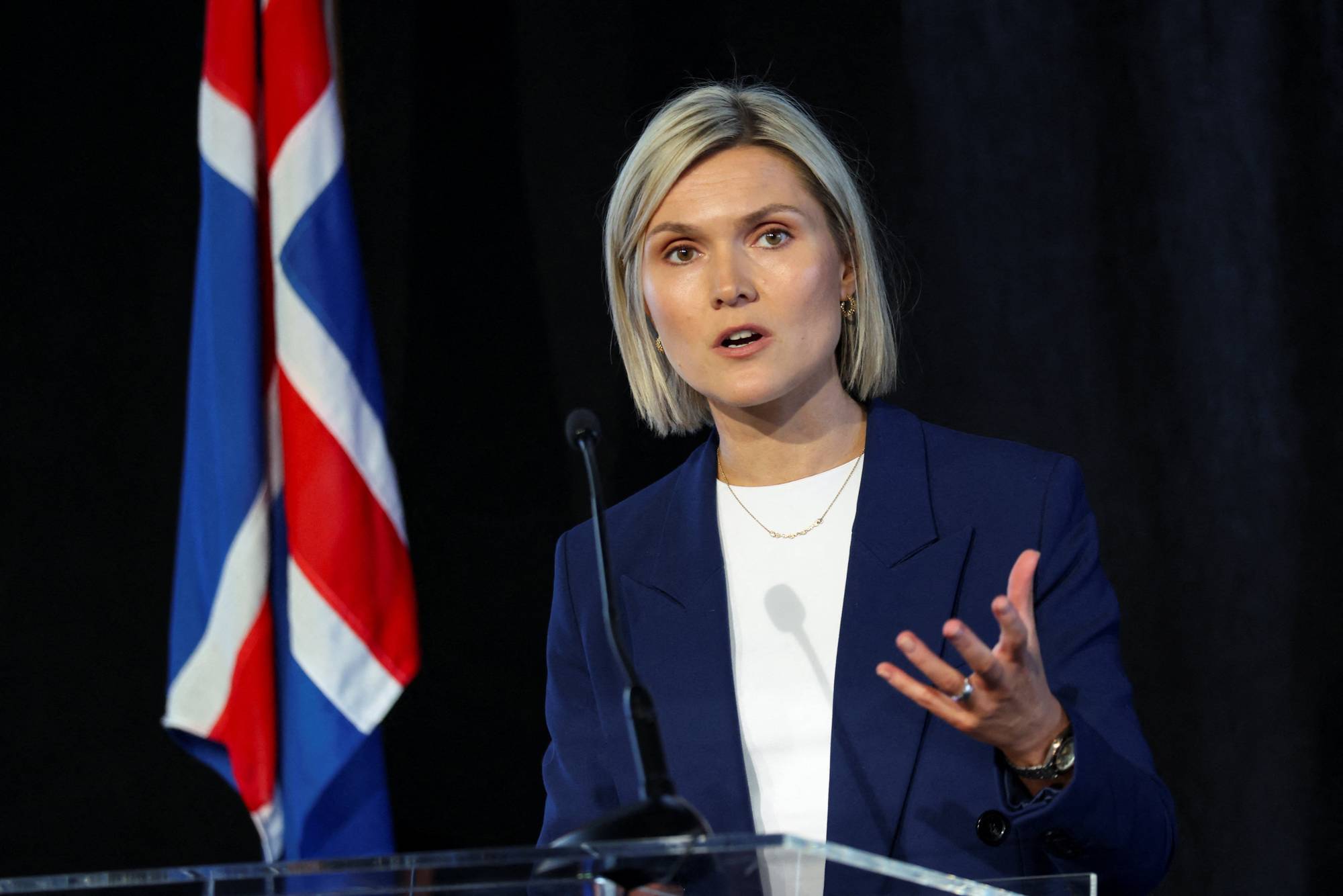 Iceland's Prime Minister Kristrun Frostadottir taler ved en talerstol med det islandske flagget i bakgrunnen. (Bildebeskrivelsen er laget av en KI-tjeneste)