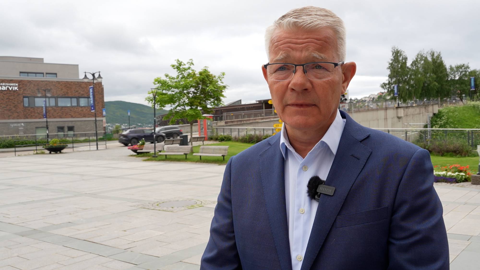 Voksen mann med blå dress og briller. 