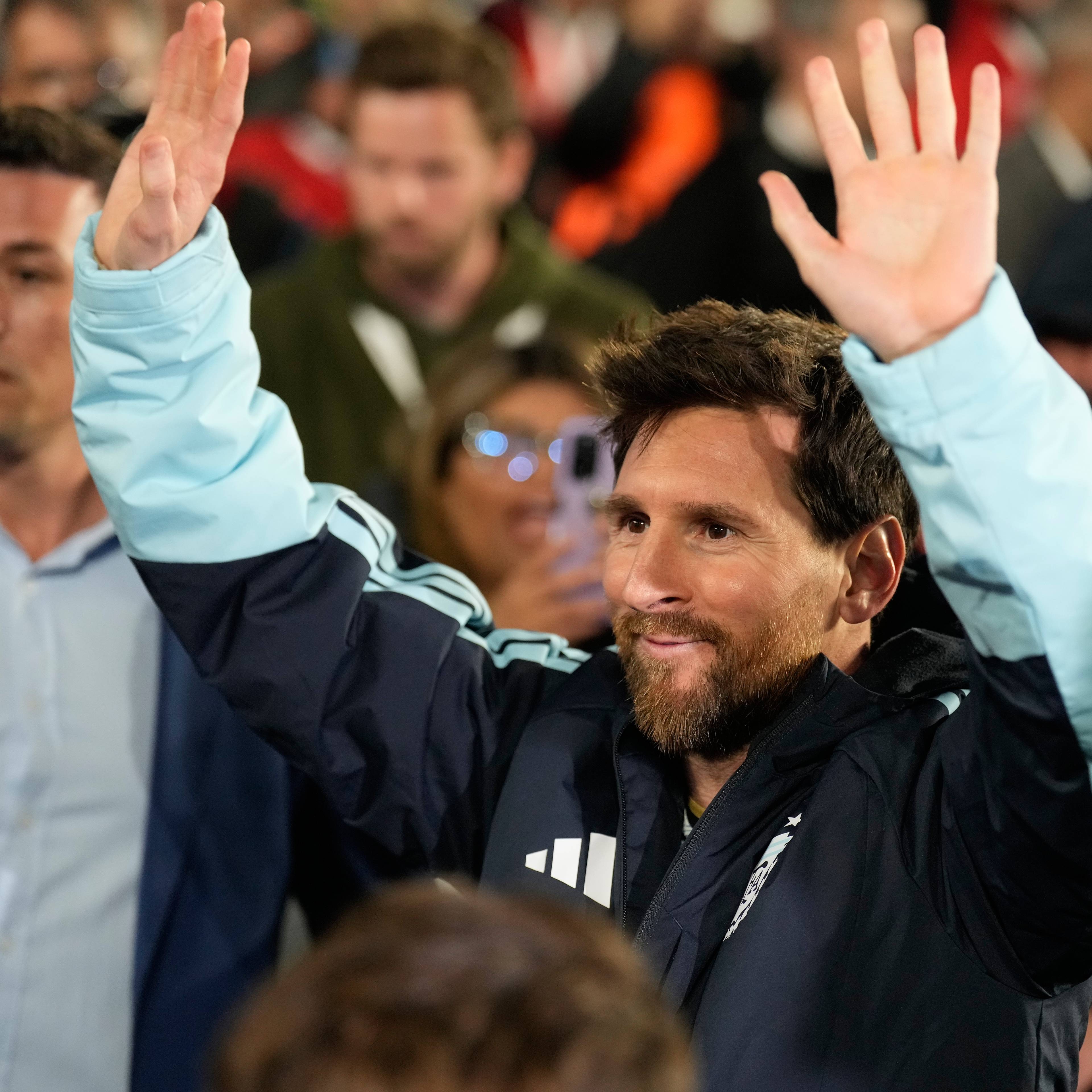 Lionel Messi vinker til folkemengden omgitt av mennesker. (Bildebeskrivelsen er laget av en KI-tjeneste)