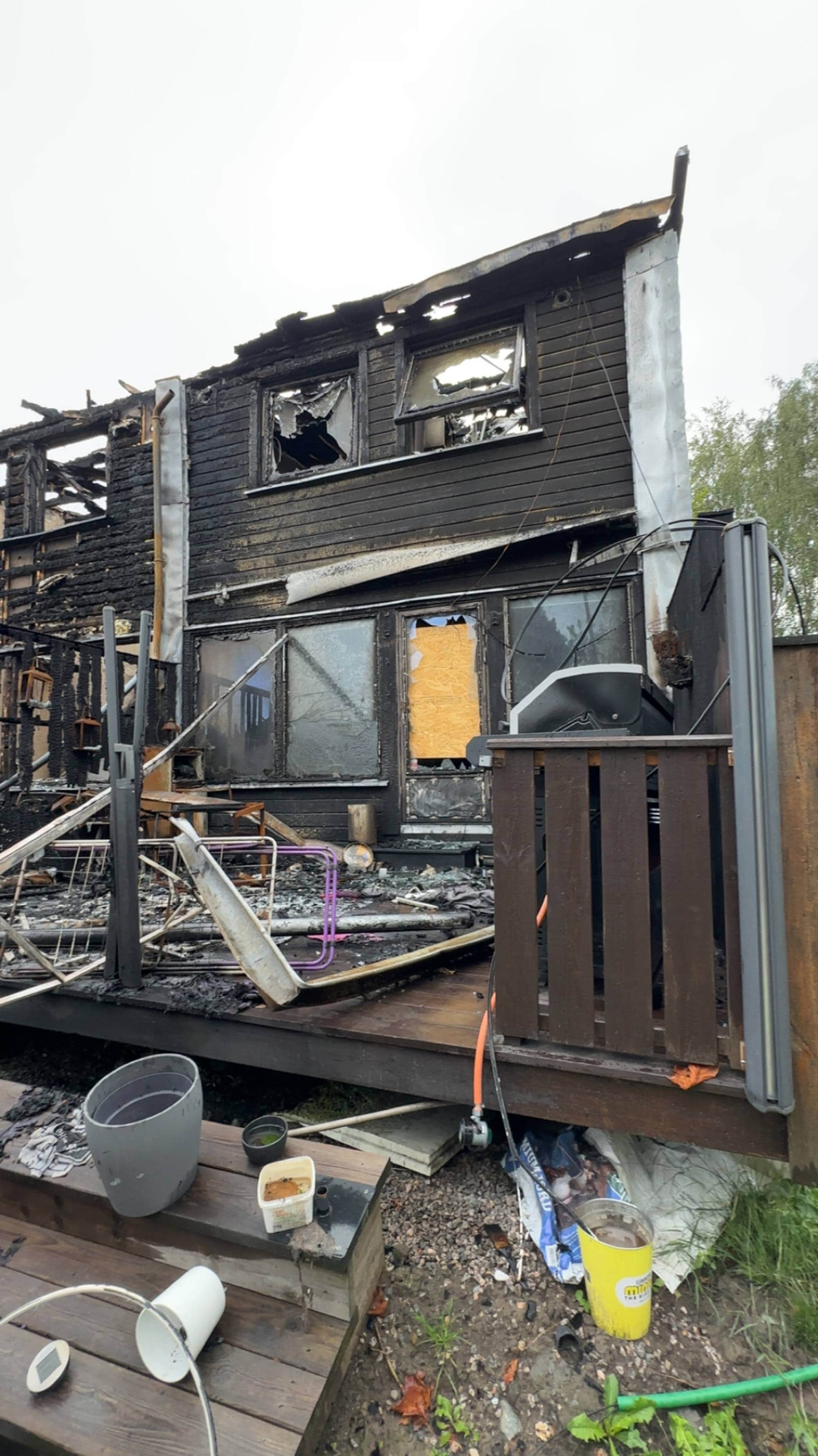 Brannskadet enebolig med knuste vinduer og ødelagt terrasse etter brann. (Bildebeskrivelsen er laget av en KI-tjeneste)