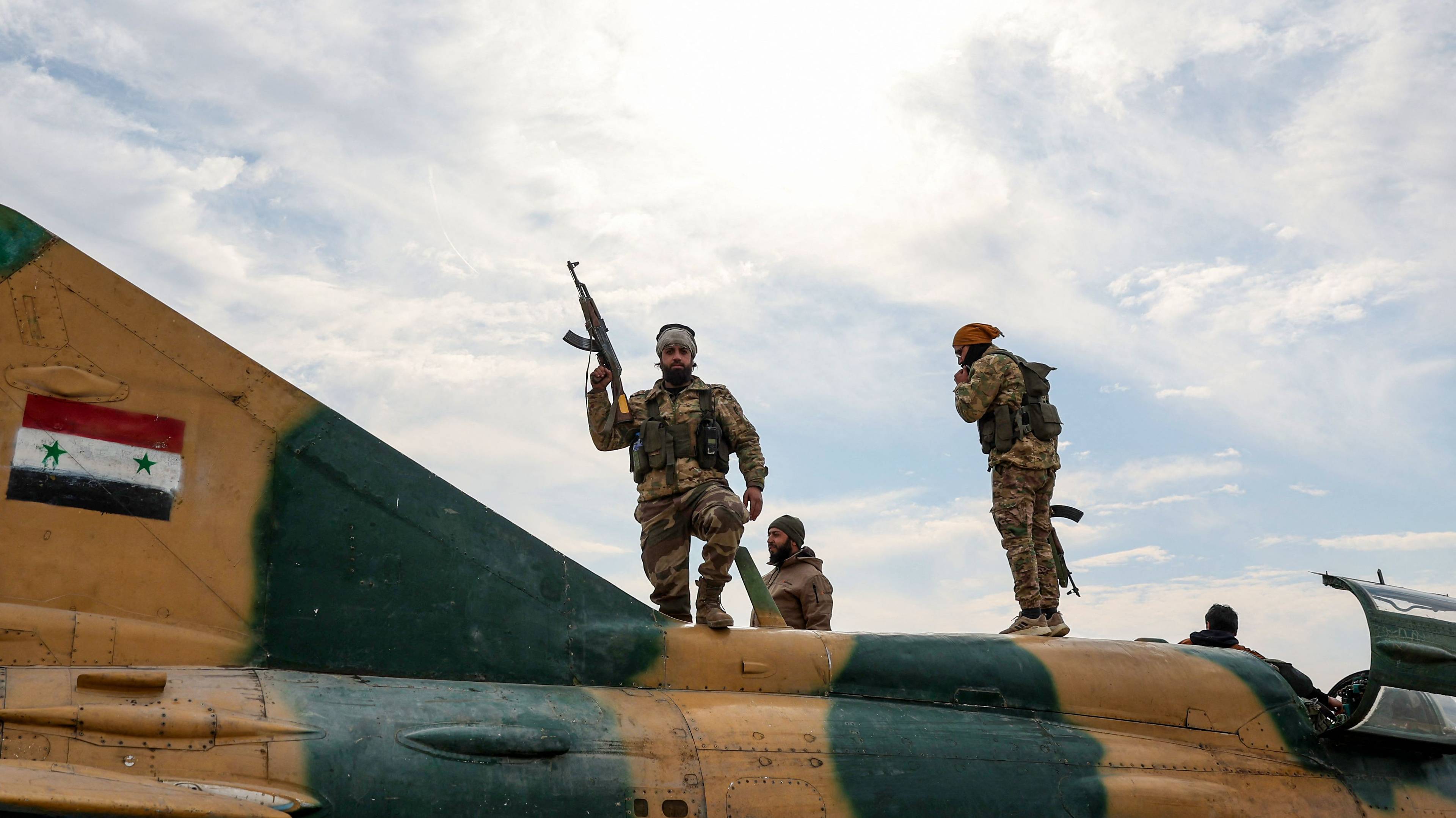 Rebel​ soldiers‌ stand ⁣on top of a syrian ⁤military plane after they captured a military ⁣airbase near the city of Hama, December 6, 2024.