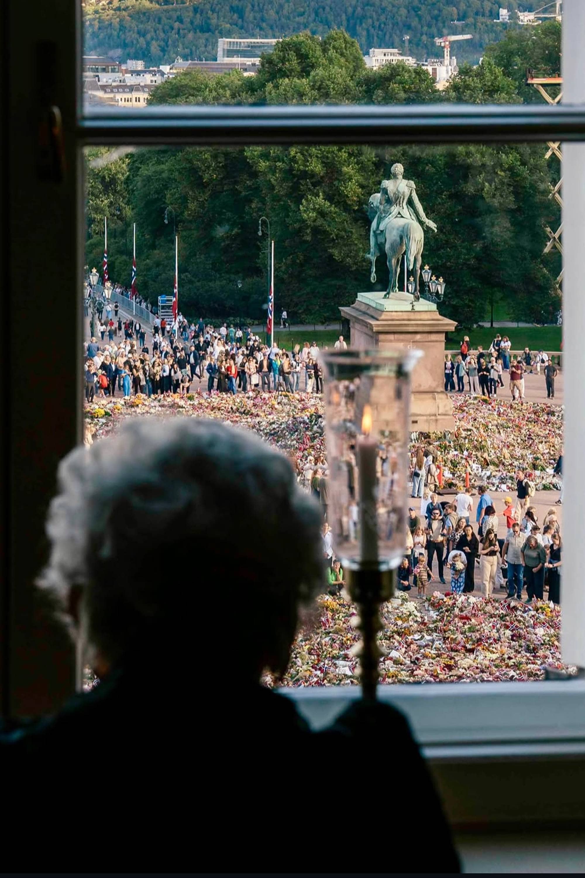 Prinsesse Astrid sitter i vinduet på Slottet og ser ut på blomsterhavet.