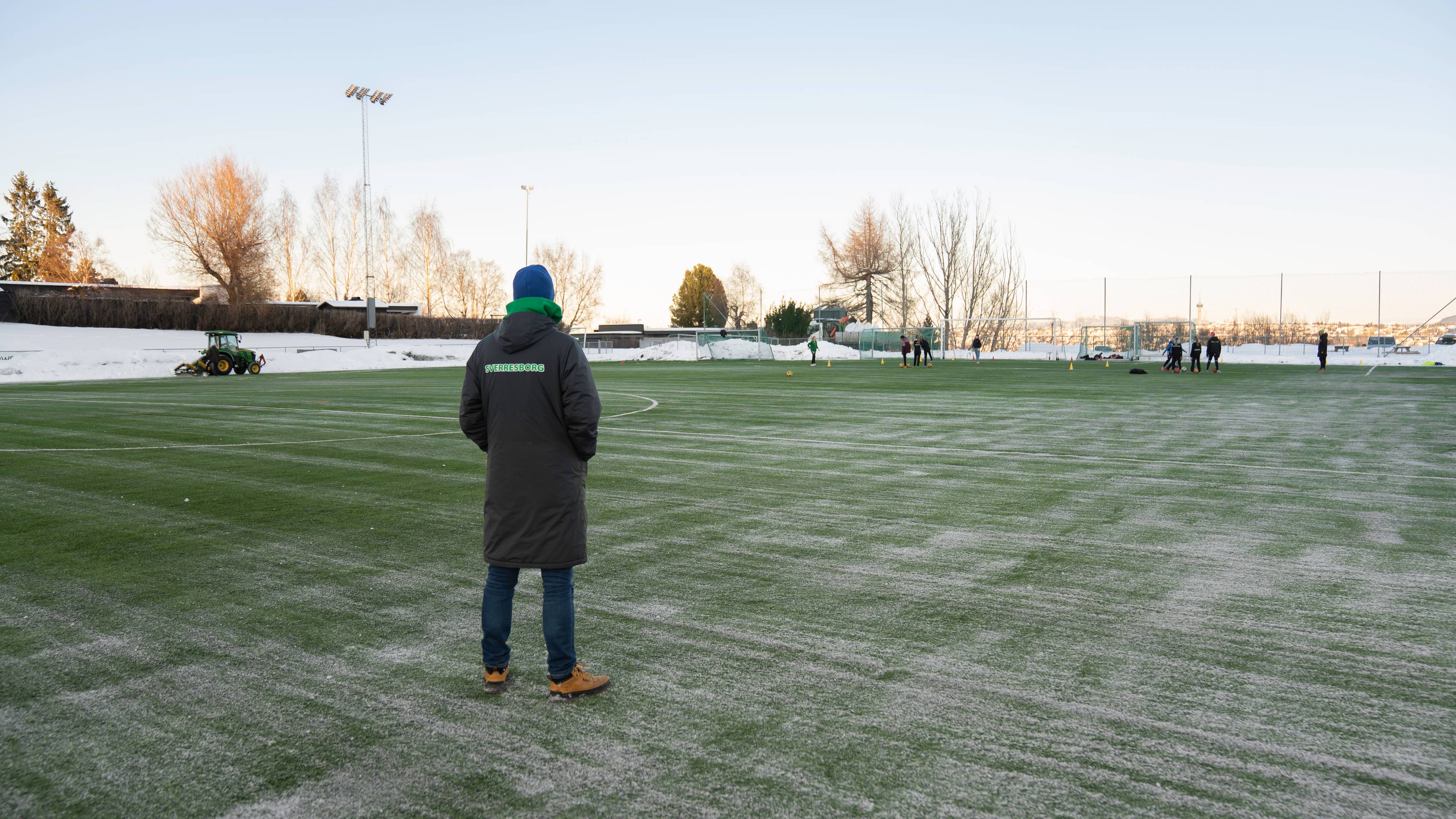 Mann står ute på en fotballbane med rygge til
