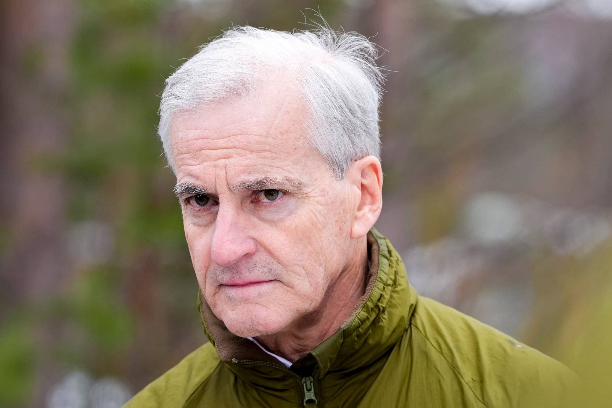 Portrett av Jonas Gahr Støre i militær vest. Han har grått hår og ser fremover. Bakgrunnen er uskarp og gir assosiasjoner til utendørsaktiviteter. (Bildebeskrivelsen er laget av en KI-tjeneste)