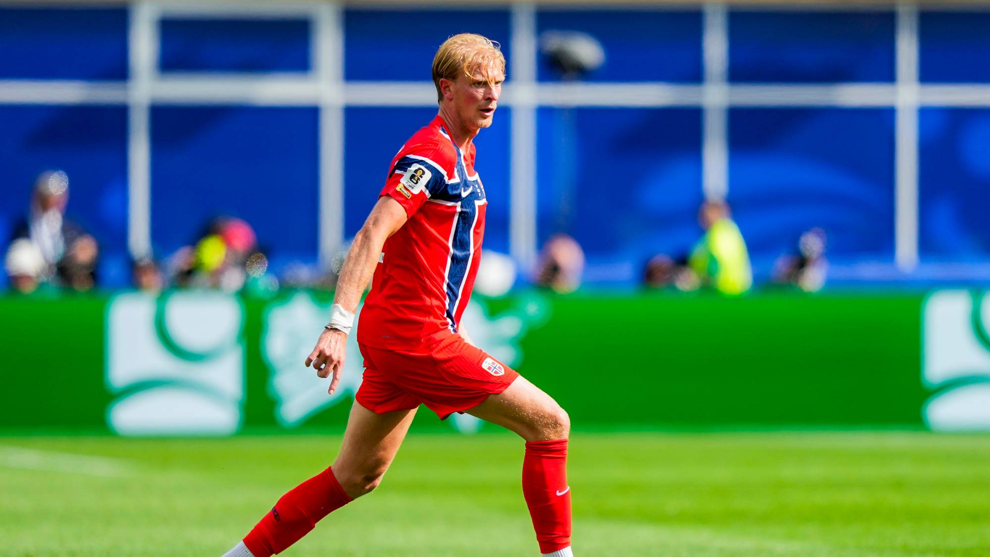 Fotballspiller i norsk landslagsdrakt fører ballen på en gressbane. (Bildebeskrivelsen er laget av en KI-tjeneste)