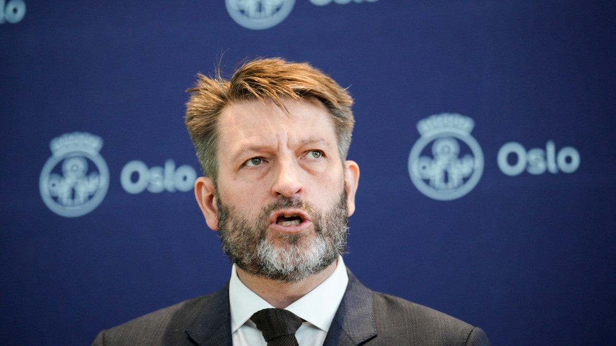 Raymond Johansen snakker foran en blå bakvegg med Oslo kommunes logo. (Bildebeskrivelsen er laget av en KI-tjeneste) FOTO: Stian Lysberg Solum/NTB