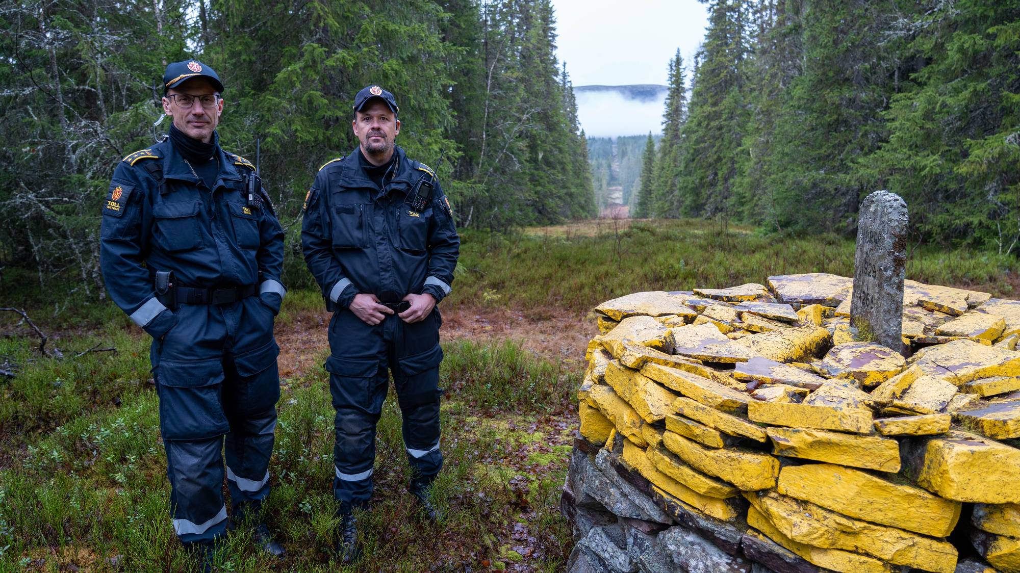 Tollbetjent Kim Holmseth og seksjonssjef Stig Hagen ved grensestein mellom Norge og Sverige