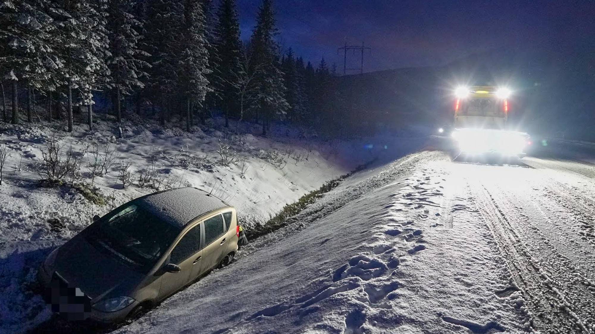 En bil som har havnet i grøfta i Sortland. Det er snø på veien og en bergingsbil med flomlys. 