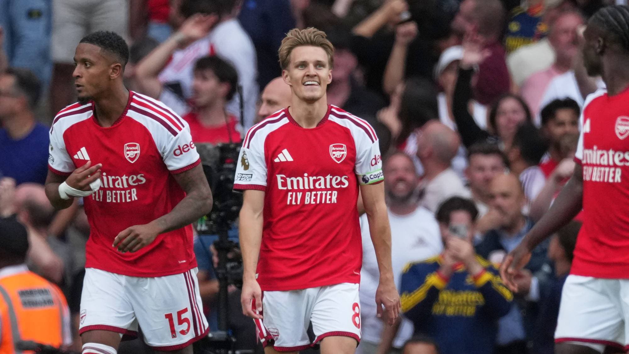 Martin Ødegaard og medspillere i Arsenal-drakter på fotballbane foran publikum. (Bildebeskrivelsen er laget av en KI-tjeneste)
