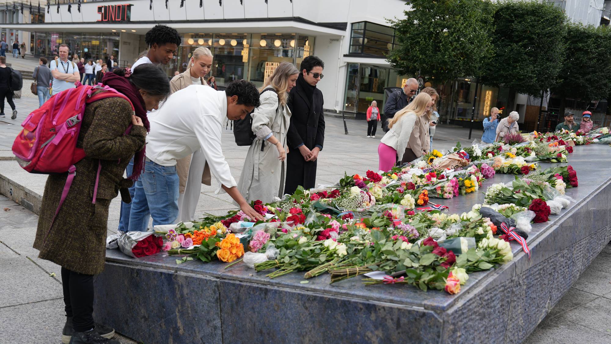 en gruppe mennesker som står rundt et bord med blomster på (Bildebeskrivelsen er laget av en KI-tjeneste)