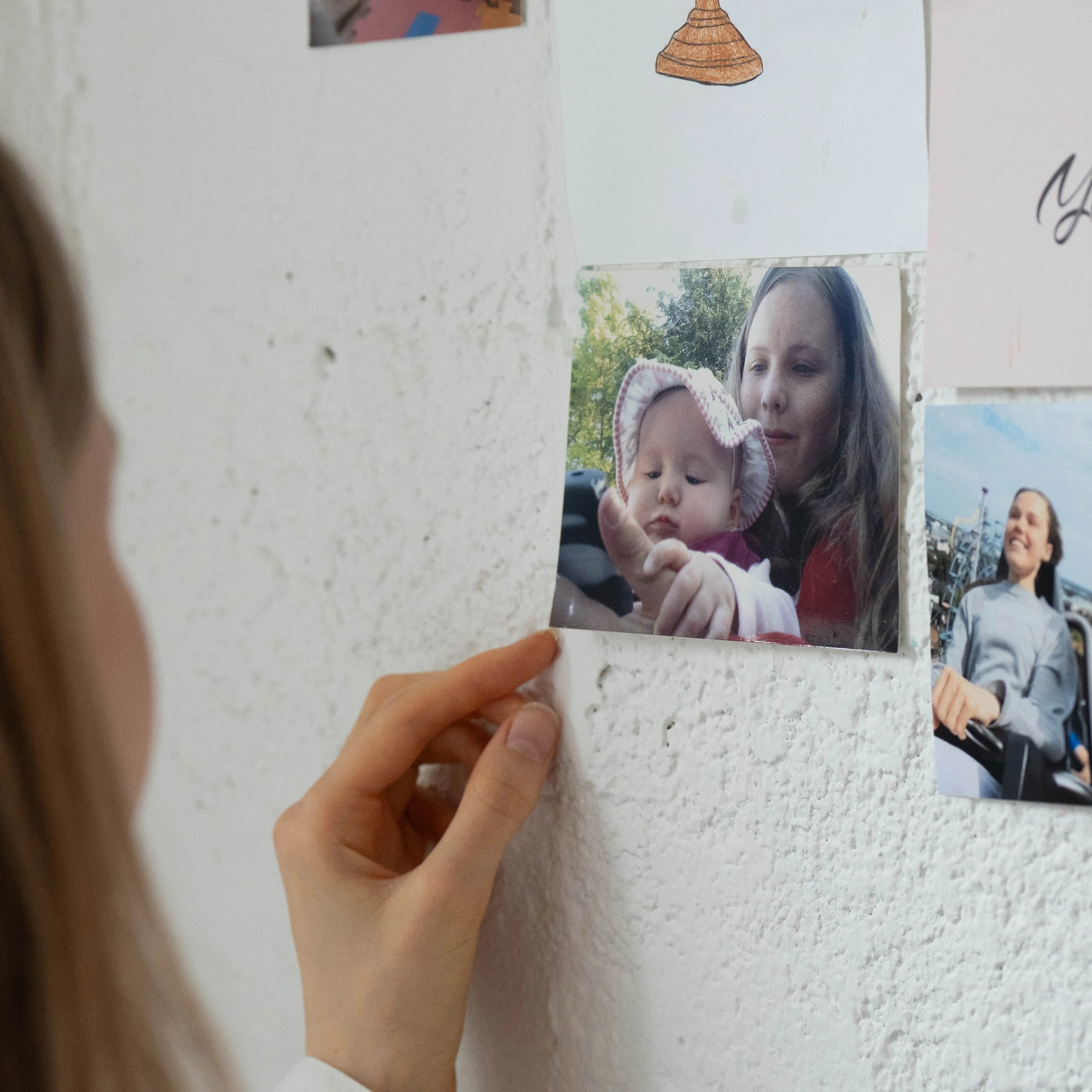 Hannah ser på et bildet som henger på veggen på soverommet. Bildet viser Hannah som liten sammen med moren hennes.