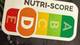 Anders Børringbo / NRK Bildet viser et nærbilde av en produktetikett med Nutri-Score, som viser en vurdering fra E til A. Det er også andre symboler og merker i nærheten, men fokuset er på Nutri-Score. Etiketten er plassert på en mørk bakgrunn som kan tilhøre emballasje. Ingen personer eller handlinger er avbildet.