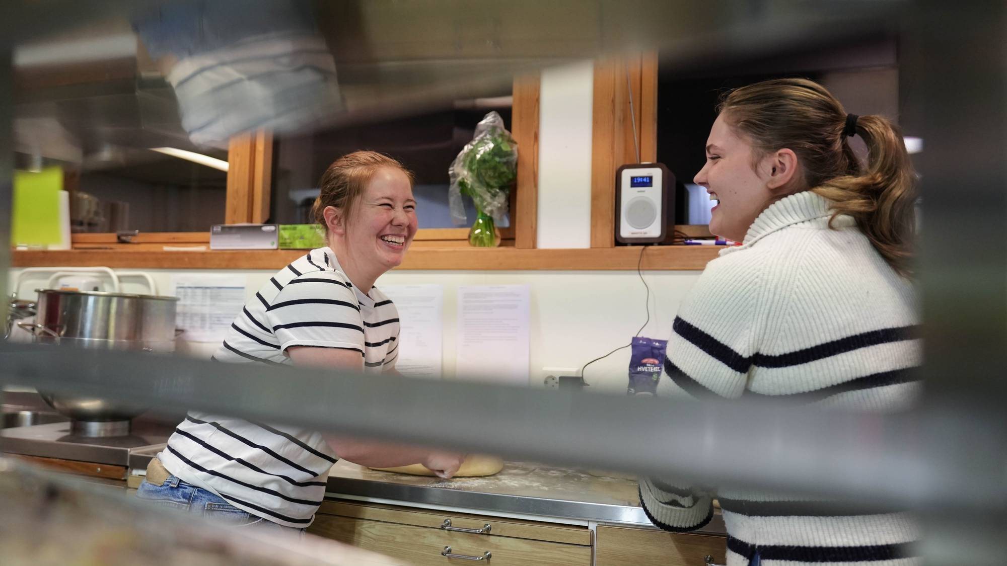 To unge kvinner som baker boller og koser seg på folkehøgskole.