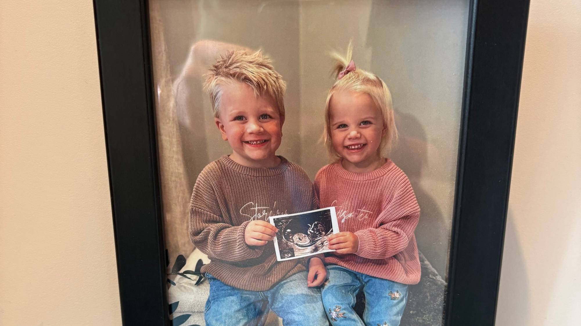 eit bilete som syner eit innramma bilde av to ungar som smiler i kamera og viser fram eit ultralydbilde 