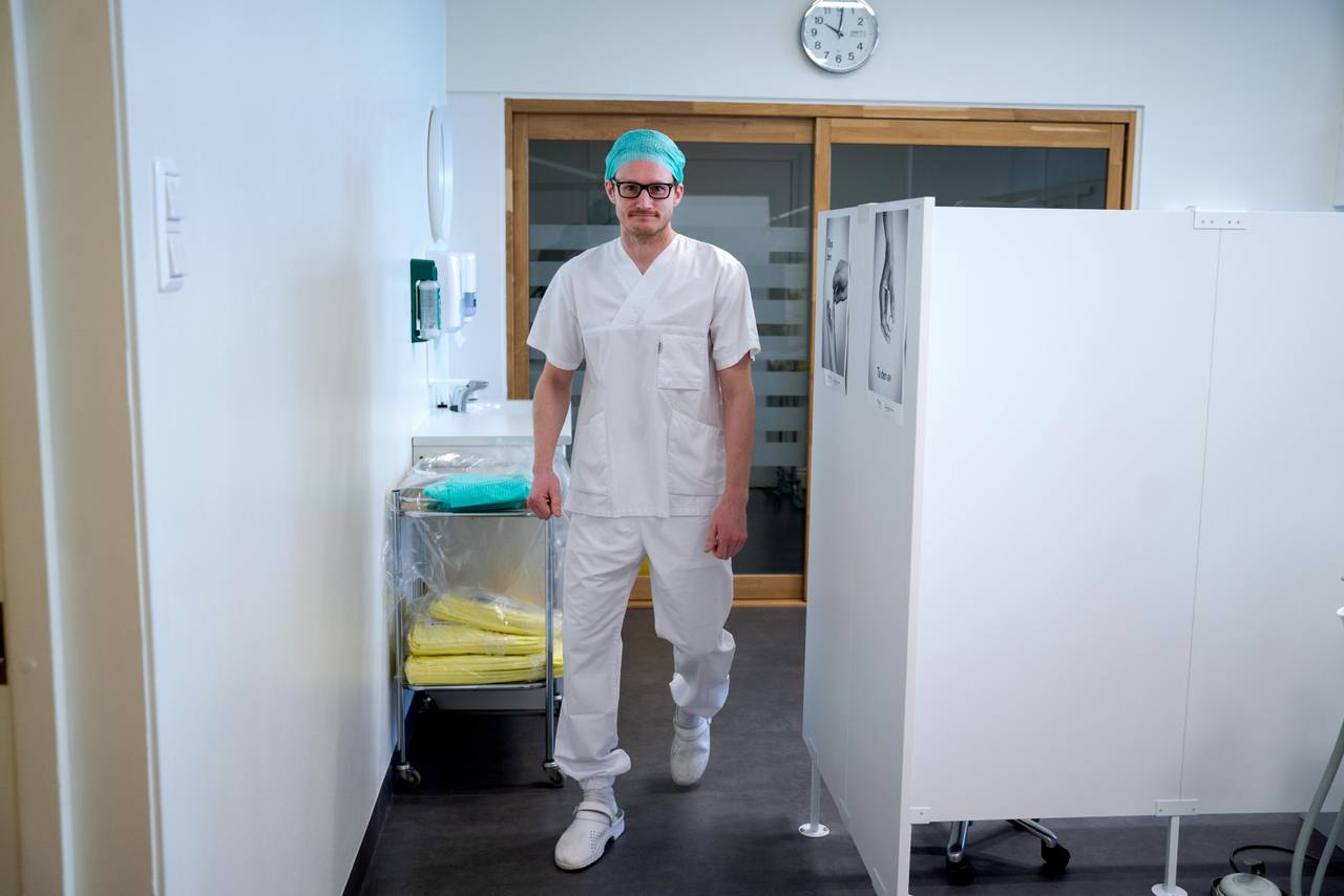 Andreas Lassen Grov går i behandlingslokalet. Han er kledd i hvite klær og hvite sko.