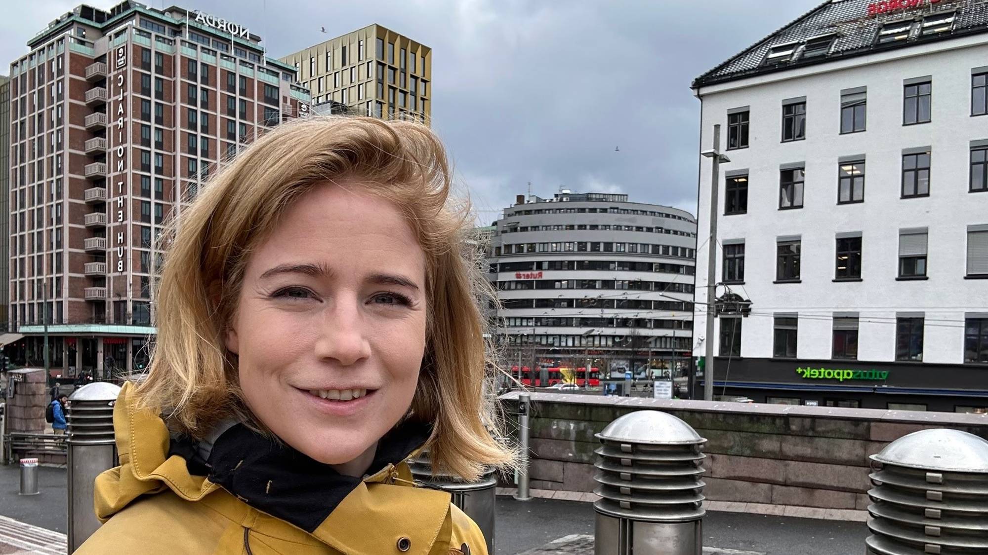 Johanne Refseth smilende i gul regnfrakk i en bygate.