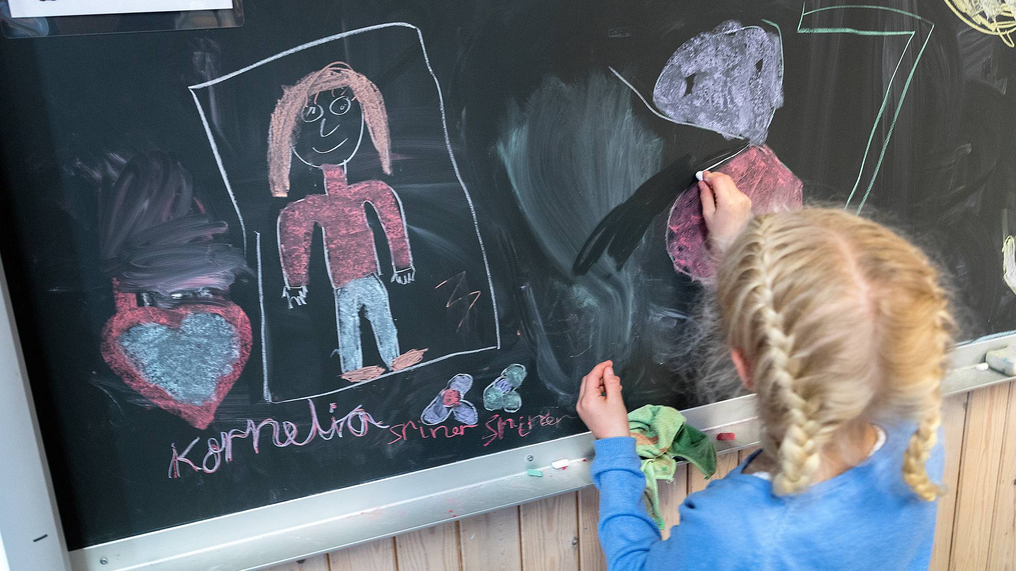 Ei jente som tegner på en skoletavle