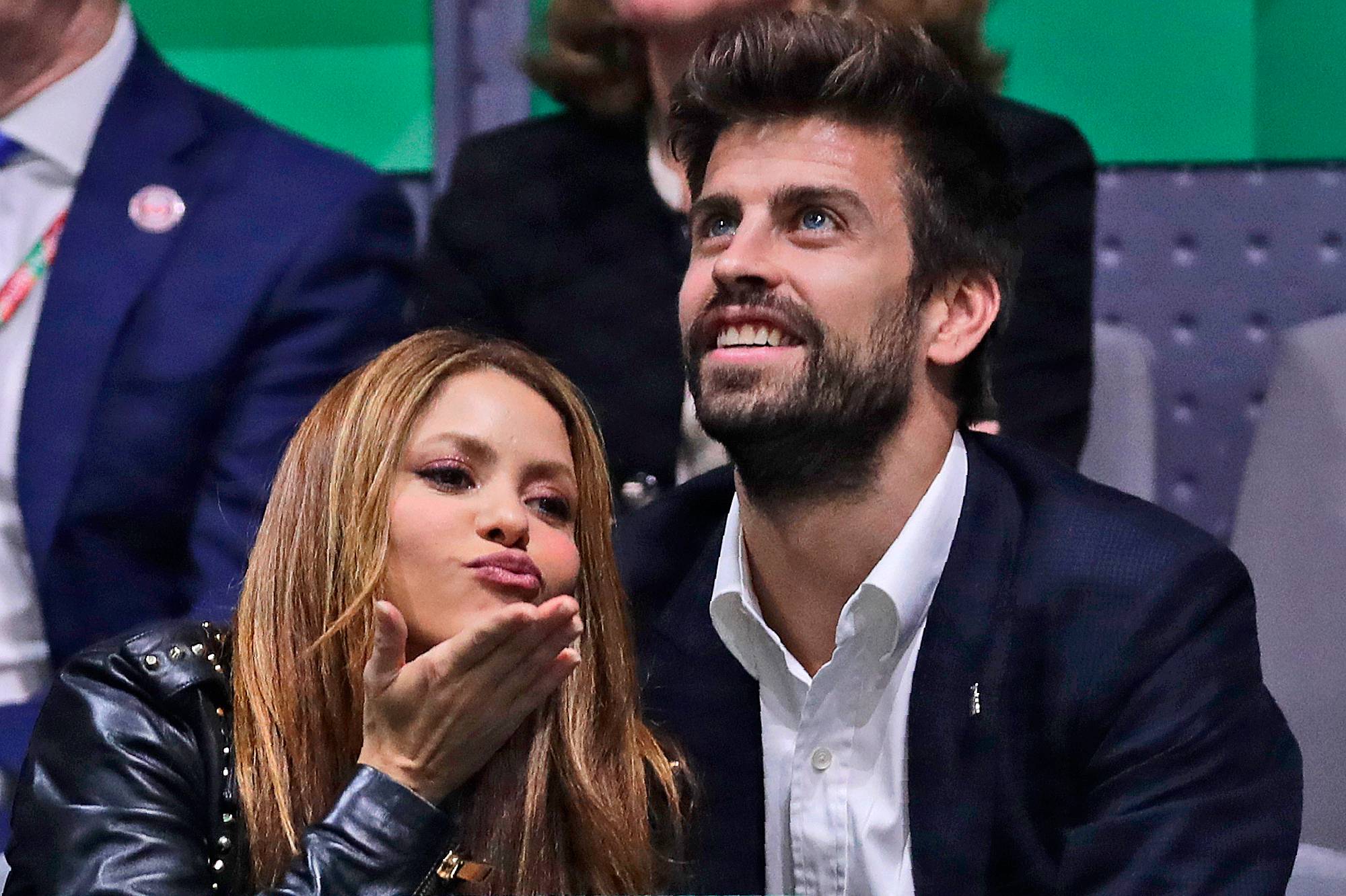 Shakira og Gerard Piqué sitter side om side under en begivenhet. Shakira kaster et kyss mot kamera. Piqué ser opp og til siden. De er begge kledd pent. (Bildebeskrivelsen er laget av en KI-tjeneste)