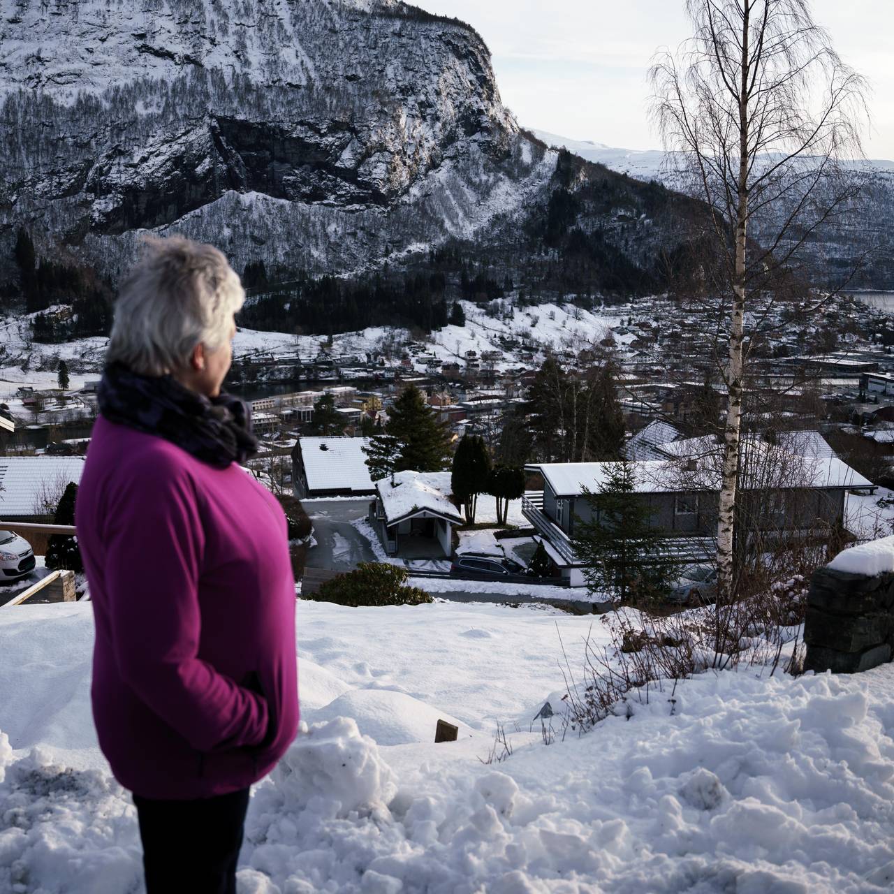 Turid ufokusert i forgrunnen ser utover bygda Oppstryn på Vestlandet.