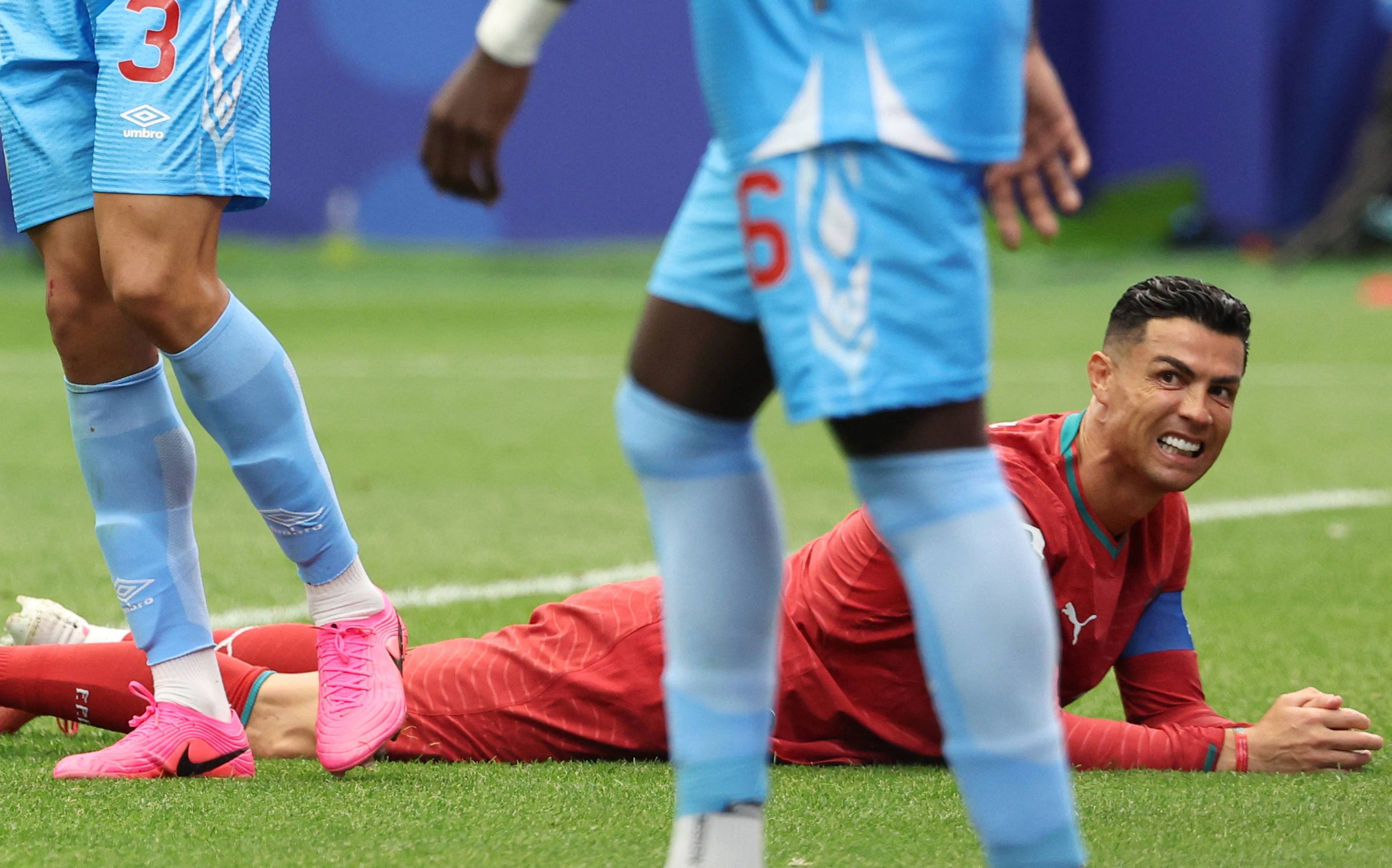 Fotballspilleren Cristiano Ronaldo ligger på gresset under en fotballkamp. Han ser mot siden mens andre spillere er i bakgrunnen. Det er en fotballkamp. (Bildebeskrivelsen er laget av en KI-tjeneste)