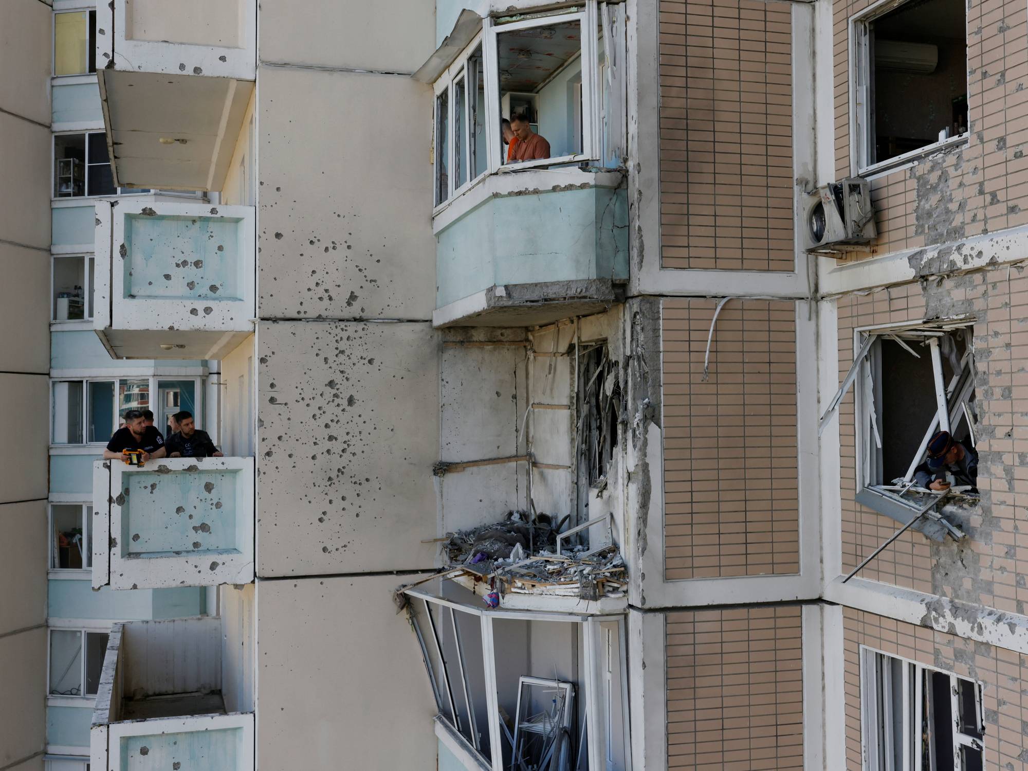 Residents clear debris from broken windows in a damaged apartment building following a Ukrainian drone attack in the course of Russia-Ukraine conflict in Krasnogorsk, in the Moscow region