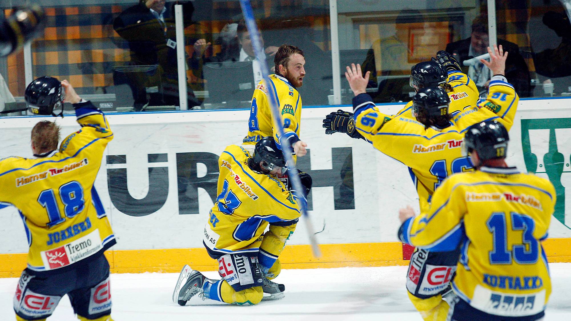 Ishockeyspillere i gule drakter jubler på isen etter scoring. (Bildebeskrivelsen er laget av en KI-tjeneste)