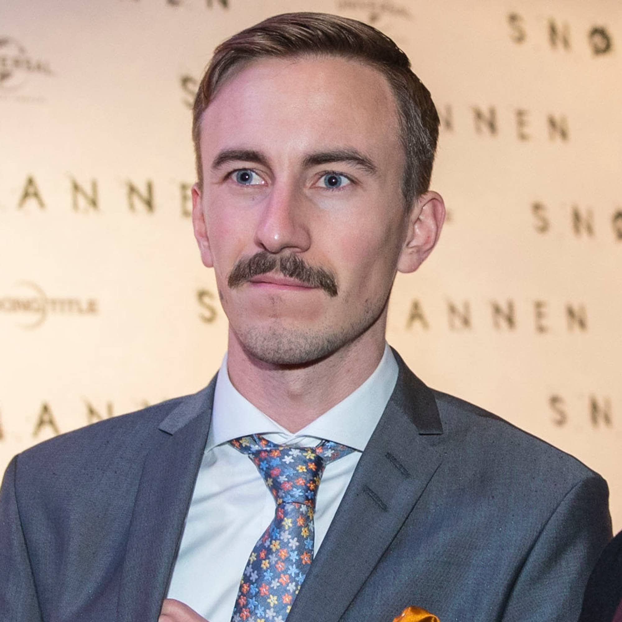 En mann og en kvinne poserer på rød løper foran et bakteppe med tittelen "Snømannen". Mannen har på seg dress, mens kvinnen har på seg en mørk jakke og et skjerf. Begge smiler til fotografen. Bakteppet inneholder gjentatte logoer fra Universal Pictures og Working Title. (Bildebeskrivelsen er laget av en KI-tjeneste)
