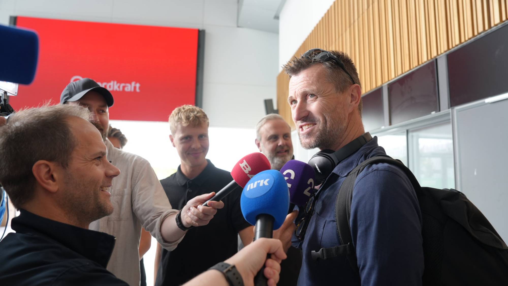 En mann blir intervjuet av flere journalister med mikrofoner. (Bildebeskrivelsen er laget av en KI-tjeneste)