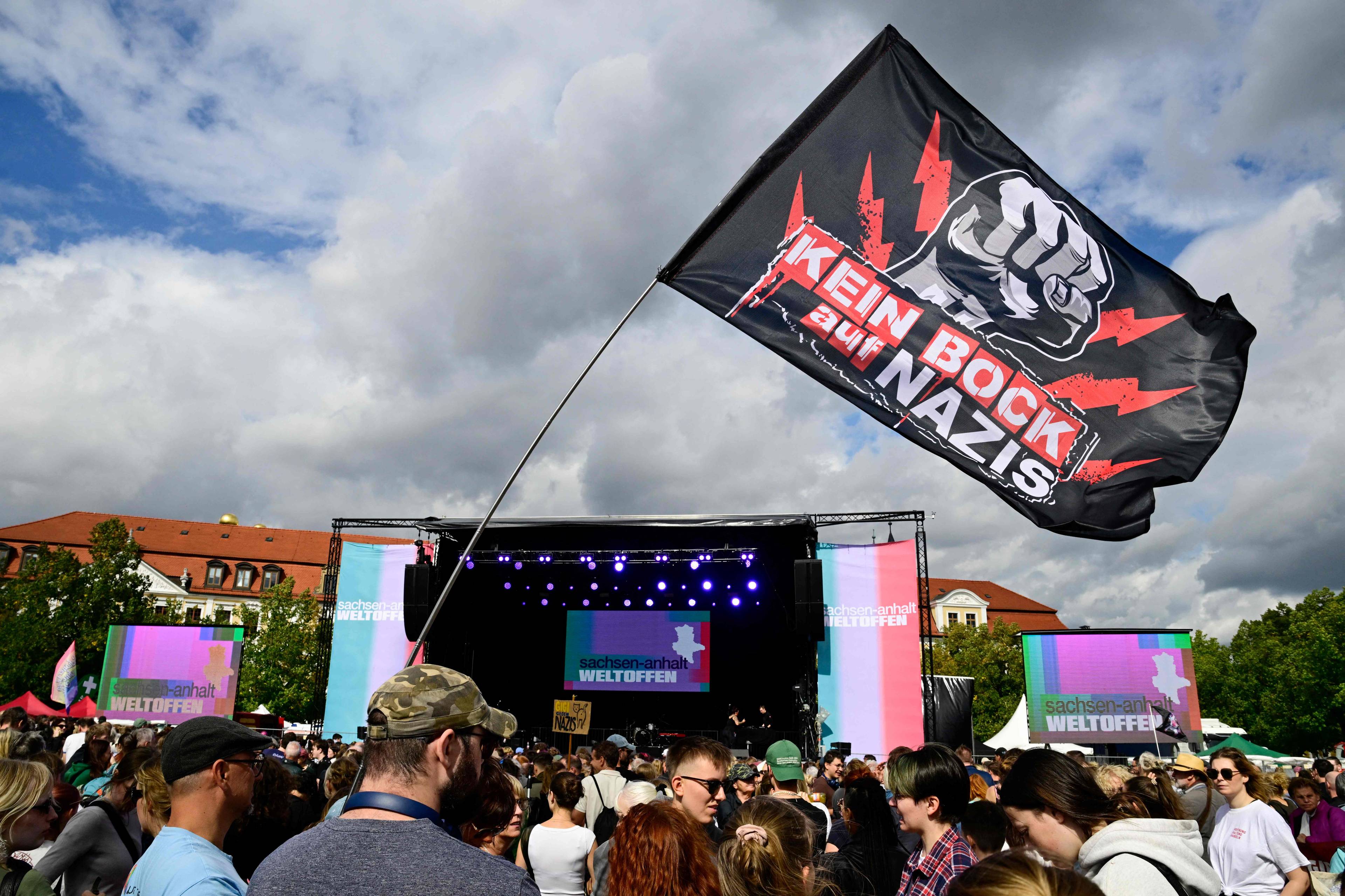 protest foran en stor scene, i forgrunnen er en plakat som sier : knus nazier