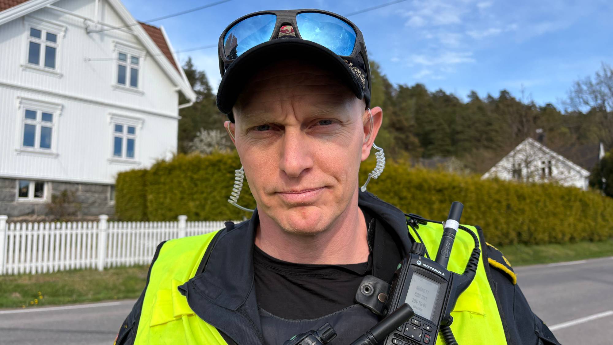 En politimann står utendørs og ser inn i kamera.