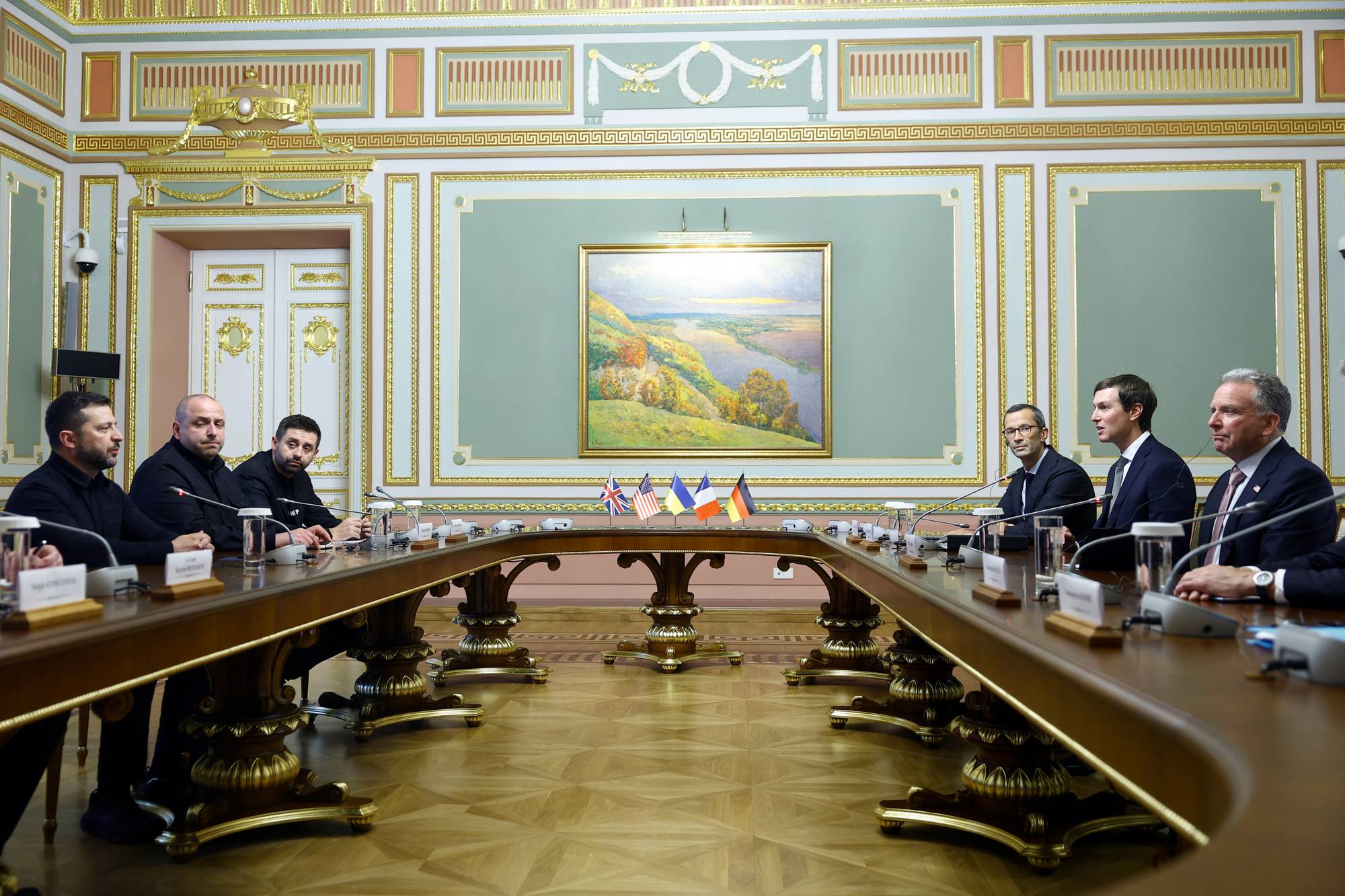 Volodymyr Zelenskyj i møte med en amerikansk delegasjon rundt et bord i et dekorert rom. (Bildebeskrivelsen er laget av en KI-tjeneste)