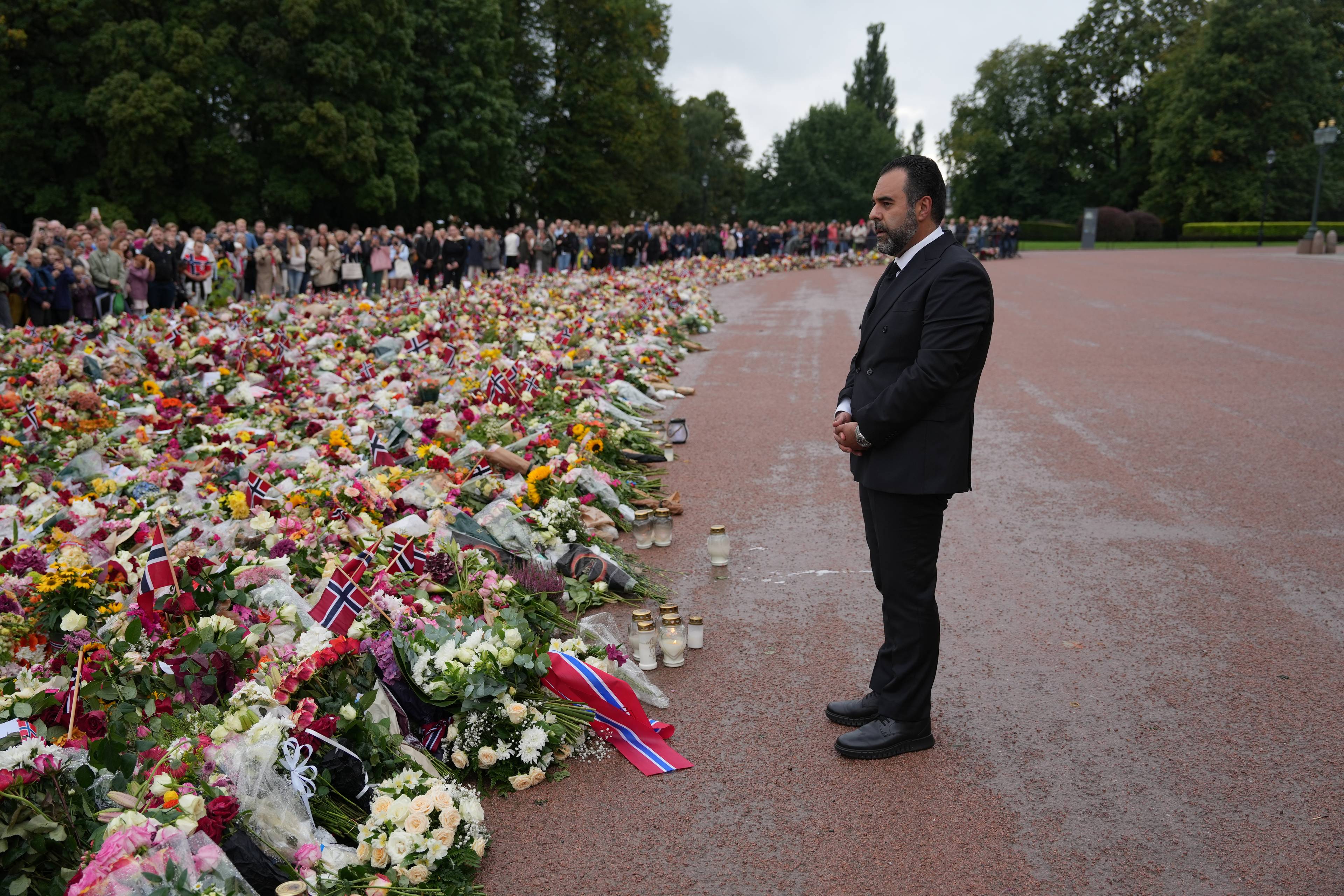 Masud Gharahkhani står ved et stort blomsterhav foran Slottet i Oslo, mens publikum ser på i bakgrunnen.