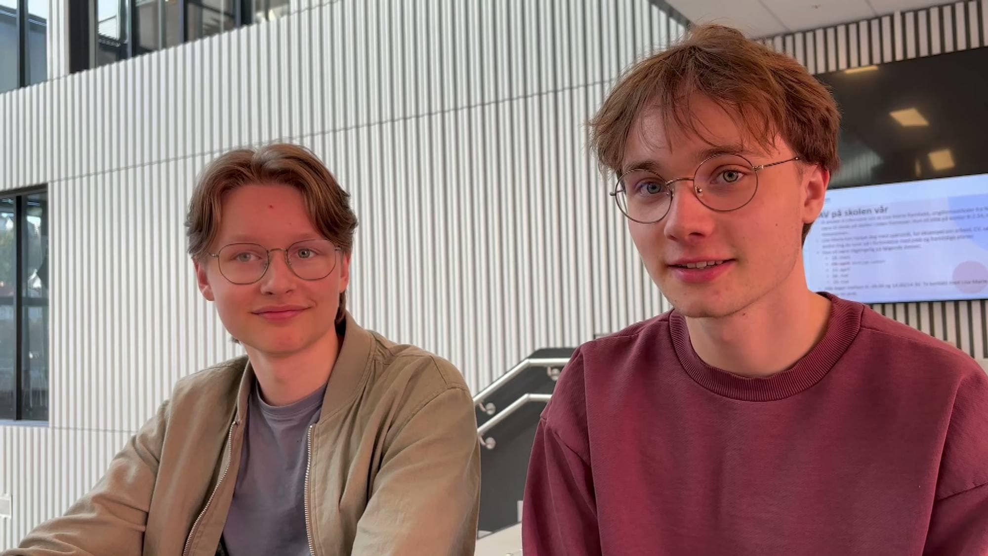 to gutter med lysebrunt hår ser i kamera. begge har briller på, en i beige jakke, han andre med bregunder genser. 