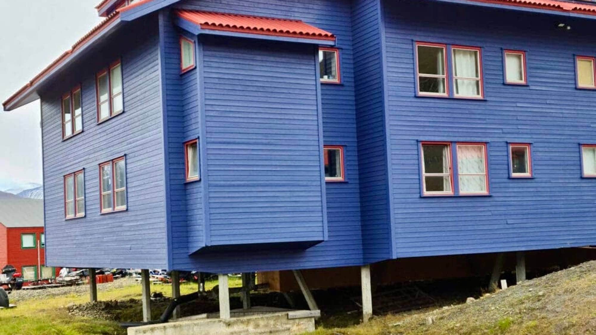Blått hus med rødt tak på pæler, Svalbard.