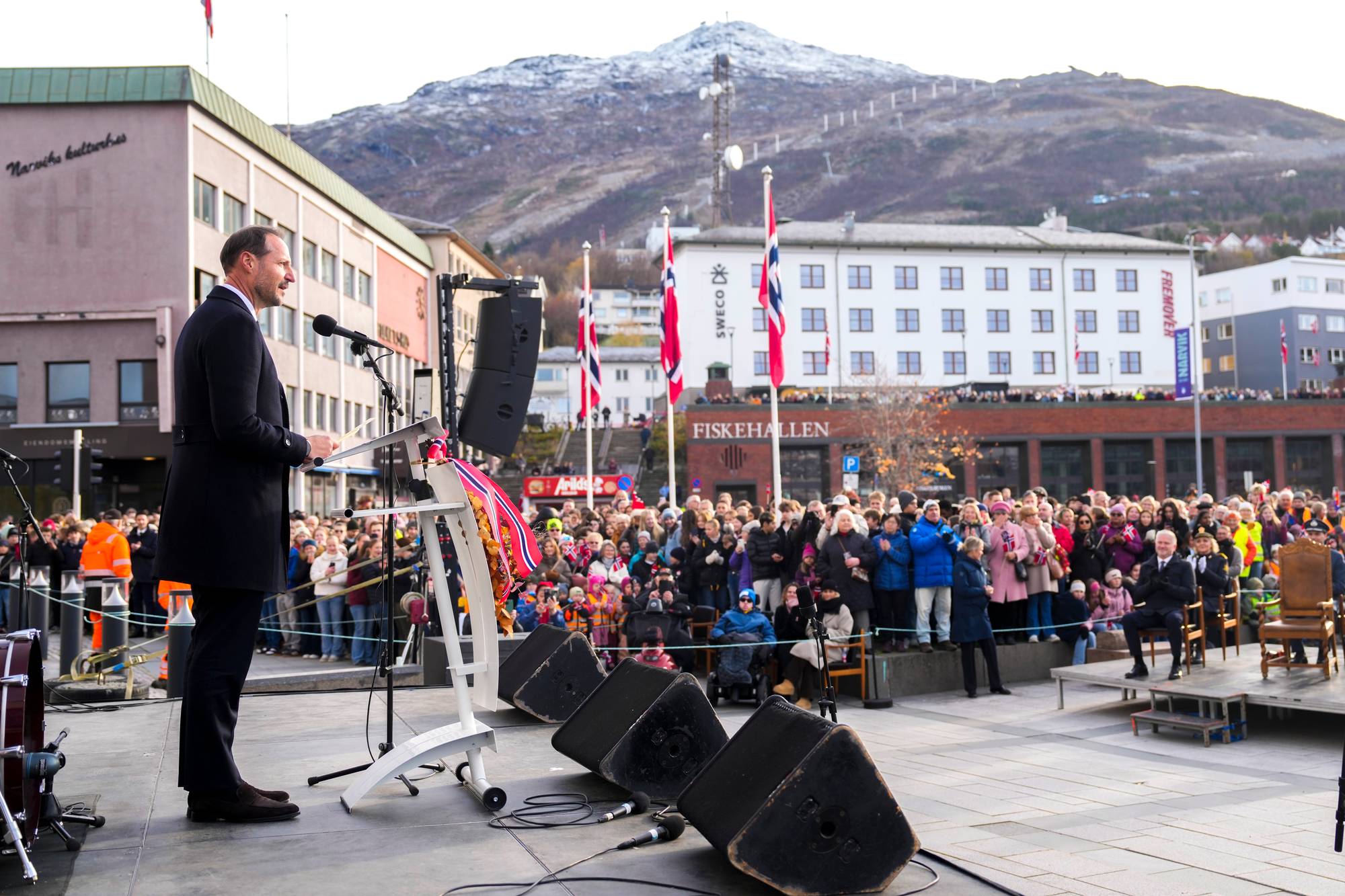 Kong Haakon taler til en folkemengde i Narvik med fjell i bakgrunnen. 