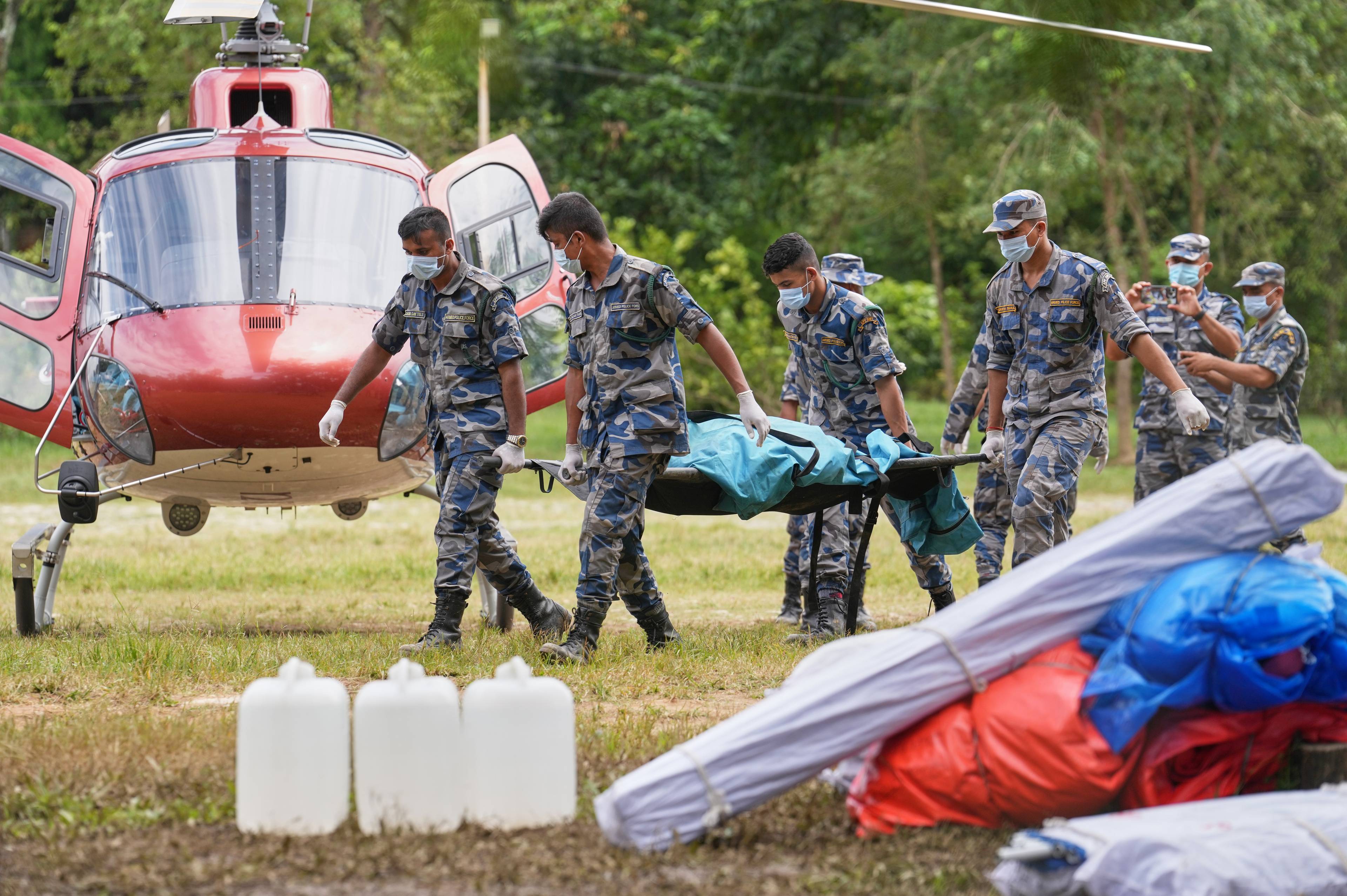 Militærpersonell i uniform bærer en båre med en pasient mot et ventende helikopter. (Bildebeskrivelsen er laget av en KI-tjeneste)