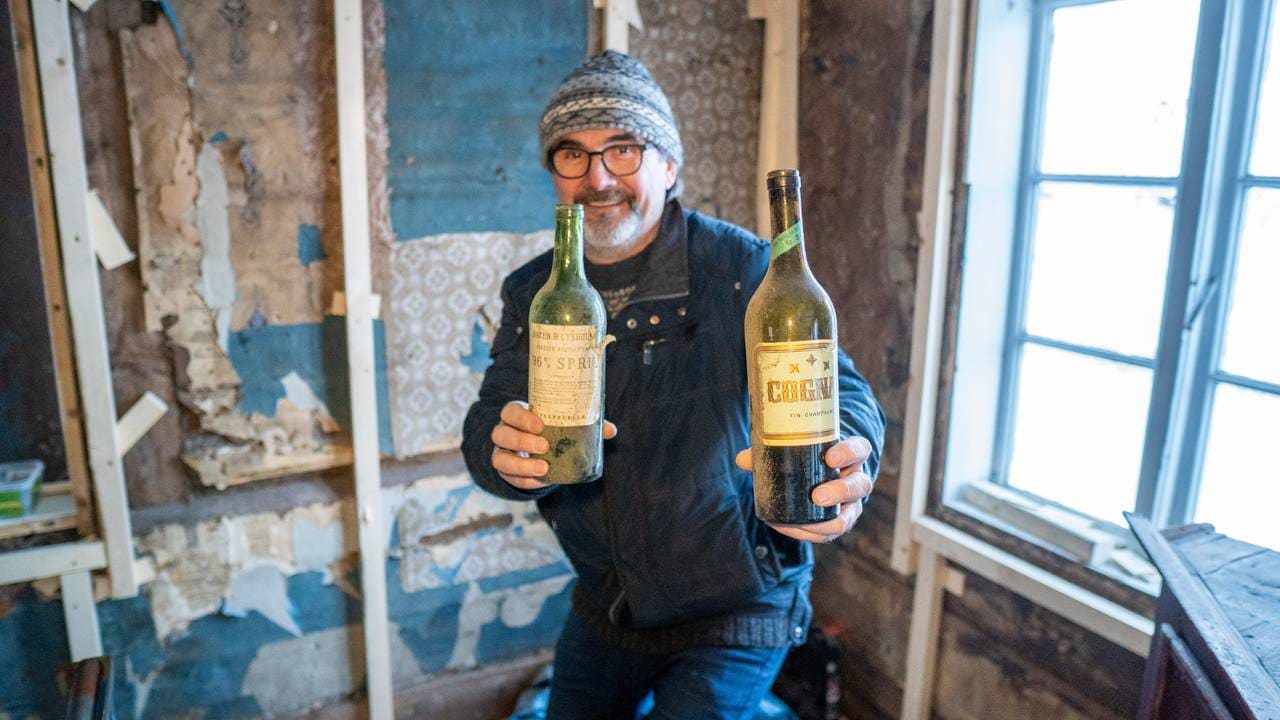 Trond Christensen viser frem spritflaskene som lå godt gjemt innunder tak og vegger.
