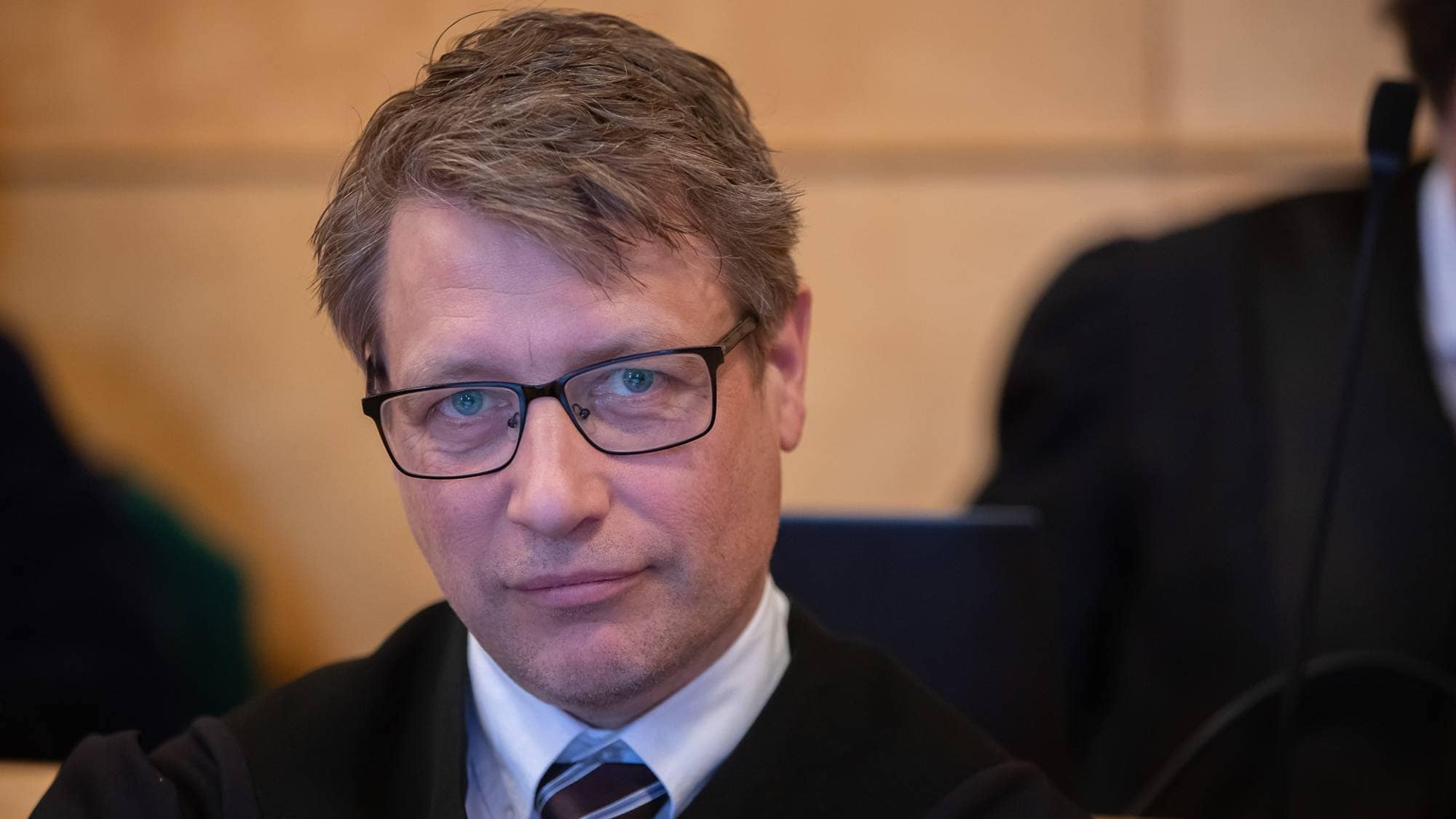 Forsvarer Ole Richard Holm-Olsen fra advokatfirmaet Wang og Holm-Olsen sitter i retten på forsvarsbenken. Han kikker rett mot fotografen og smiler forsiktig
