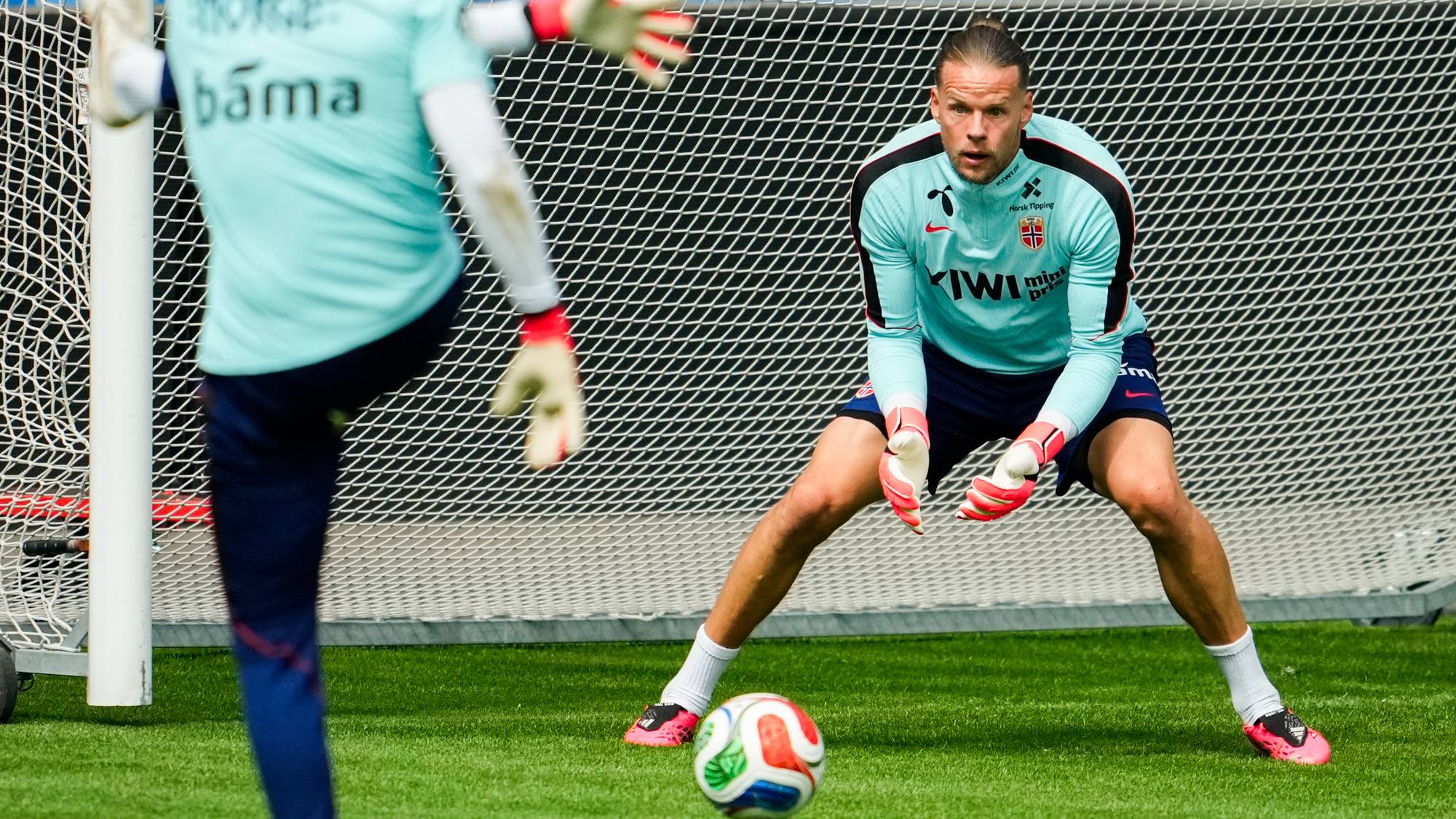 To norske fotballkeepere trener foran et mål på en gressbane. (Bildebeskrivelsen er laget av en KI-tjeneste)