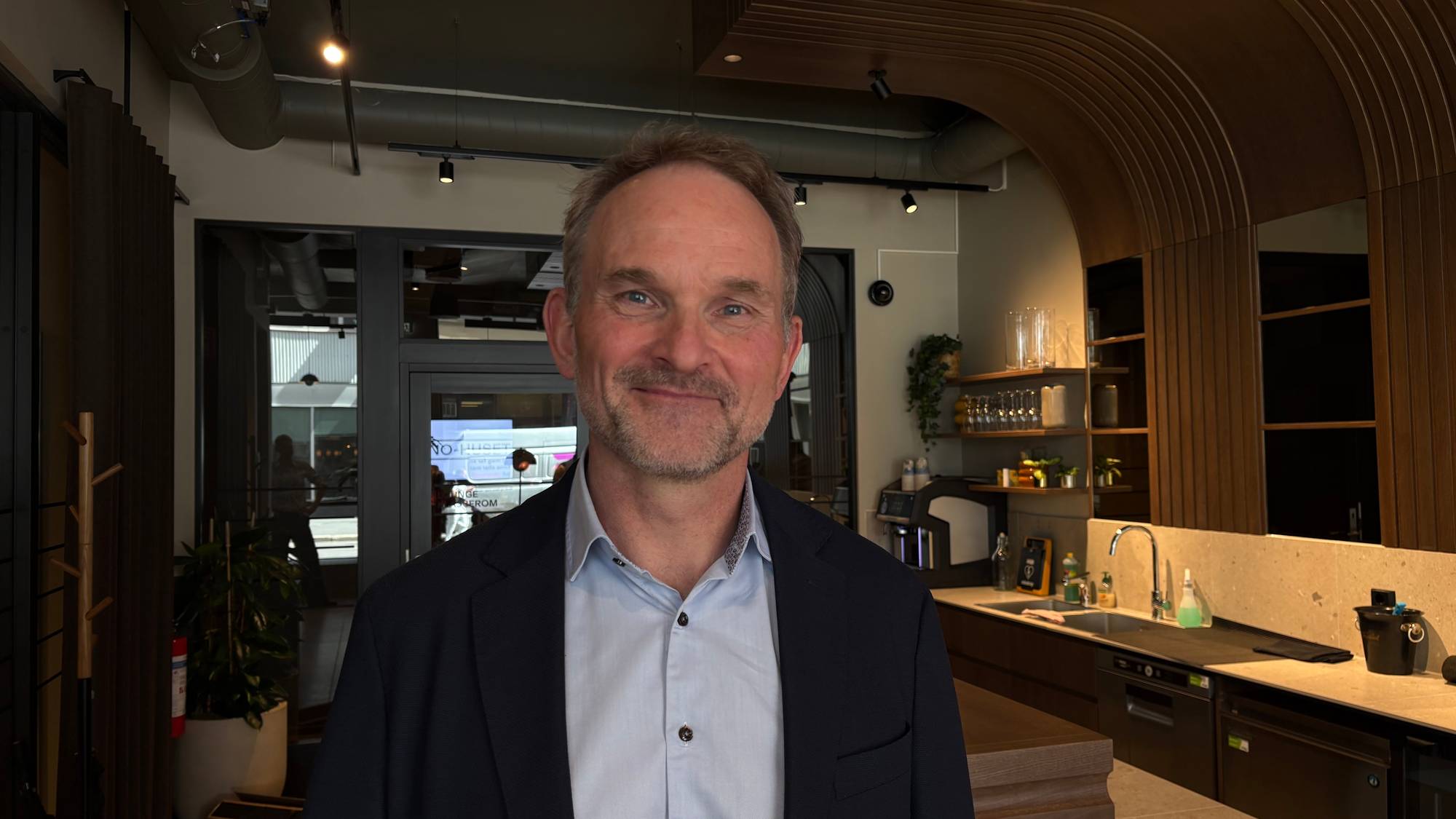 Mann med skjorte og dressjakke smiler i kamera