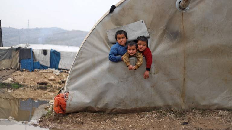 Syrian⁣ children ‍look out⁢ of their⁣ tent as heavy rain⁤ floods the⁣ al-Balea camp for internally displaced persons⁢ near ⁤the town of Jisr al-Shughur in Syria's⁤ northwestern Idlib province on January 13, 2022