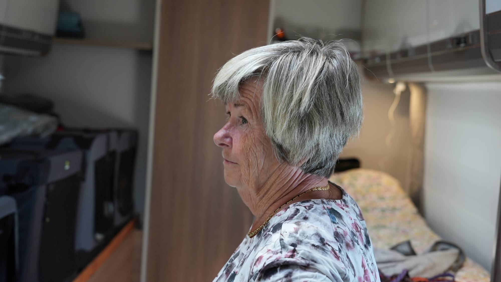 Grete er inne i bobilen sin. Hun ser oppgitt ut. Bobilen er trang og det er en seng i bakgrunnen. 