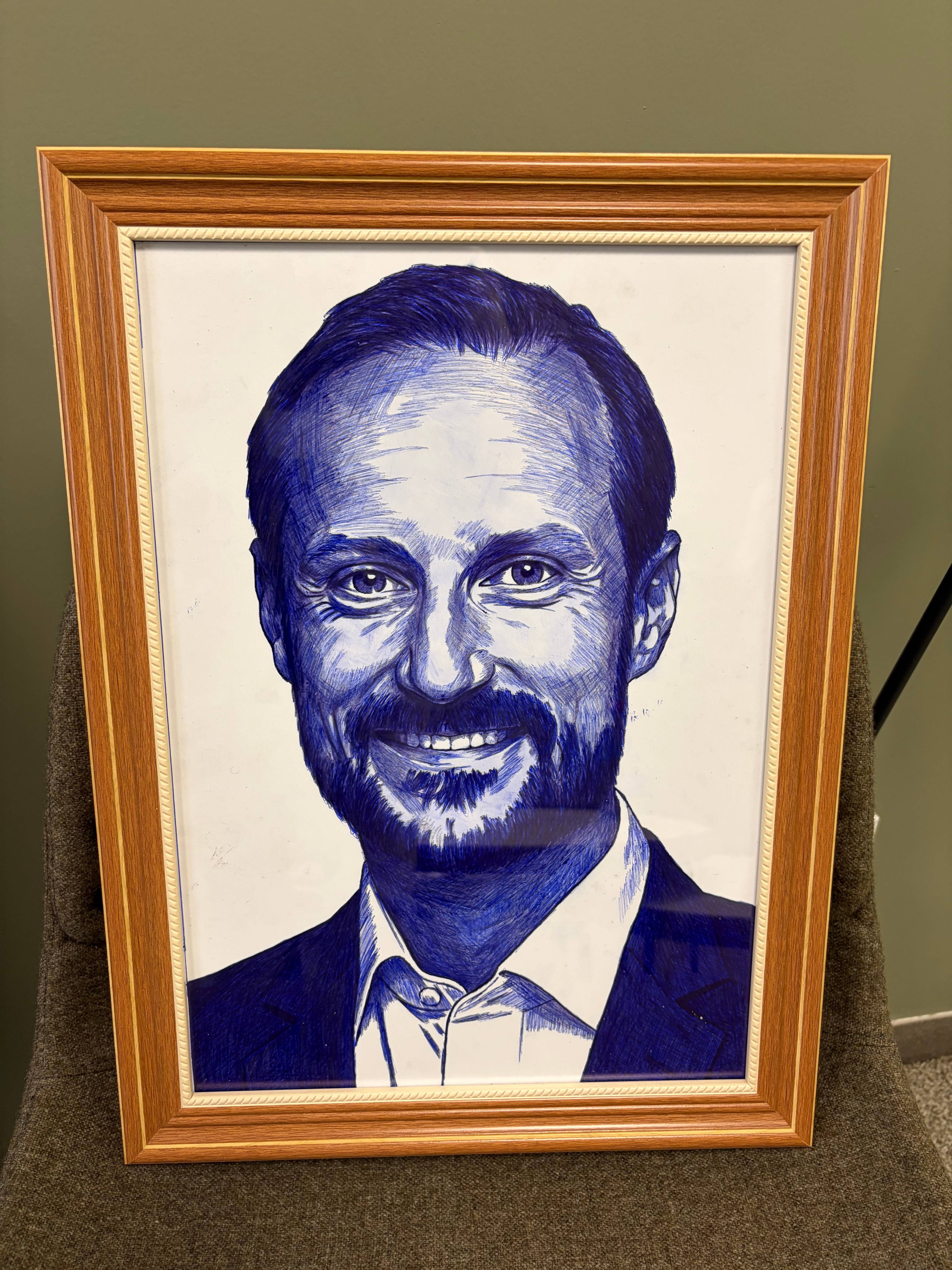 Illustrasjon i ramme av Kong Haakon utført med blå kulepenn.