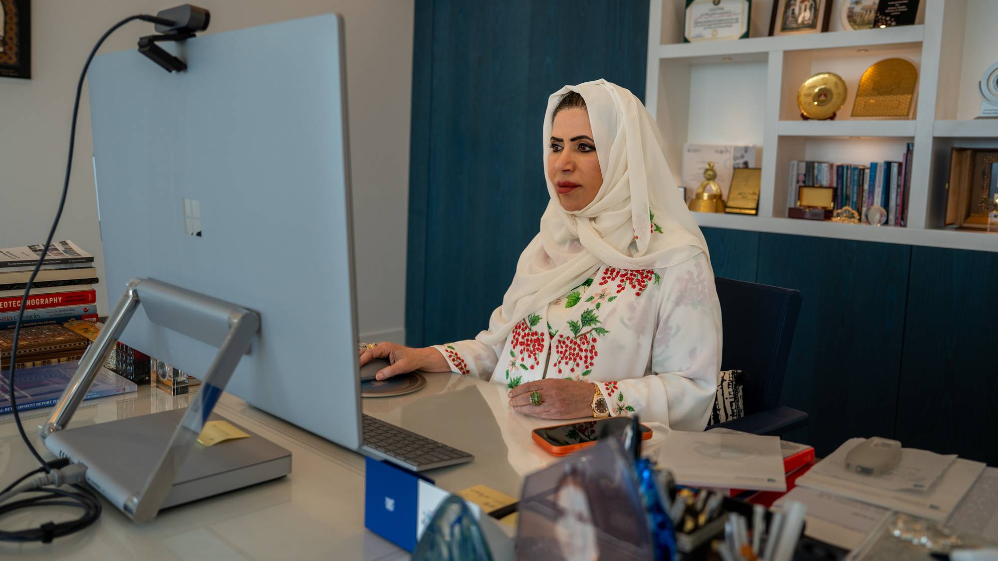 Kvinne med hvit hijab sitter foran en dataskjerm