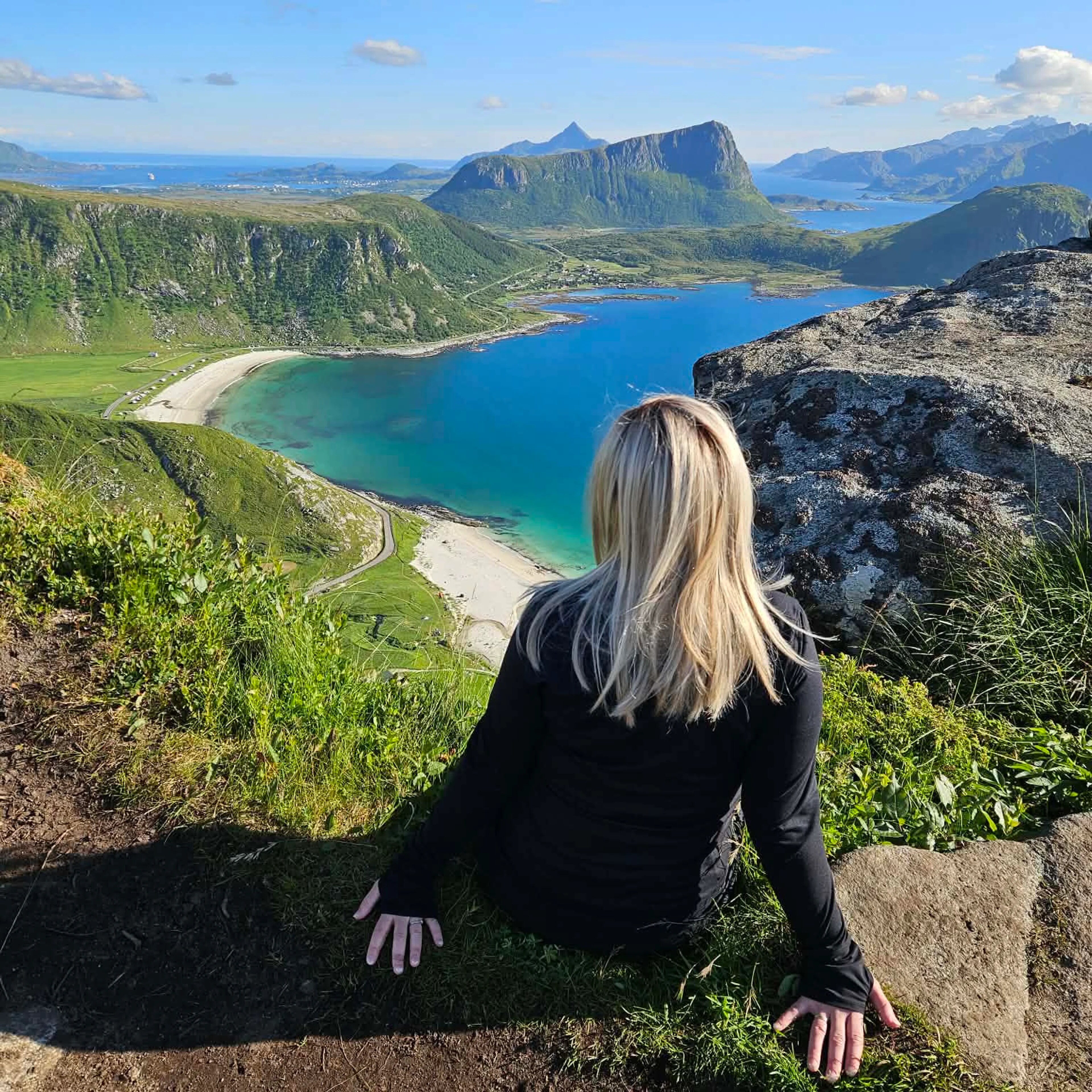 Kvinne ser ut over vakkert sunn fra en fjelltopp